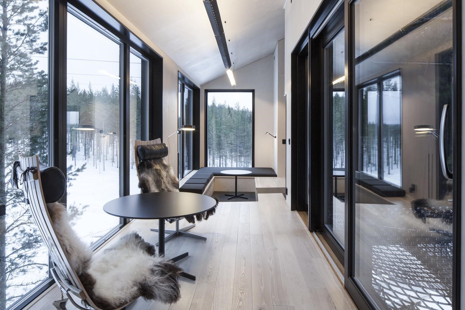 Modern interior with large windows overlooking a snowy forest HD Wallpaper