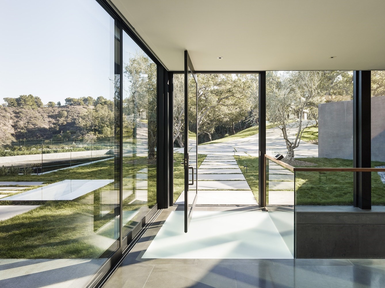 Modern glass house entrance with outdoor pathway HD Wallpaper