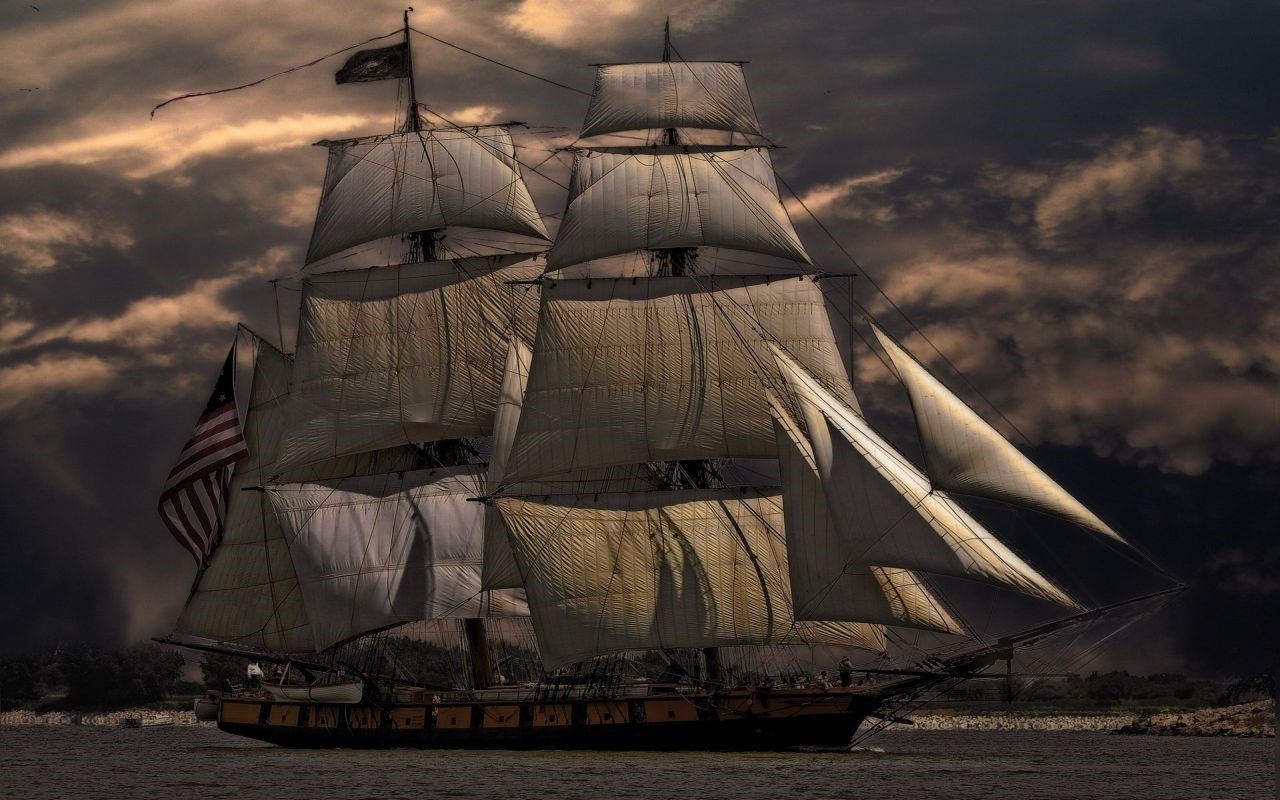 Sailing ship with American flag under stormy clouds HD Wallpaper