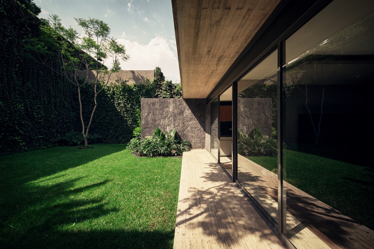 Modern house with stone wall and green lawn HD Wallpaper