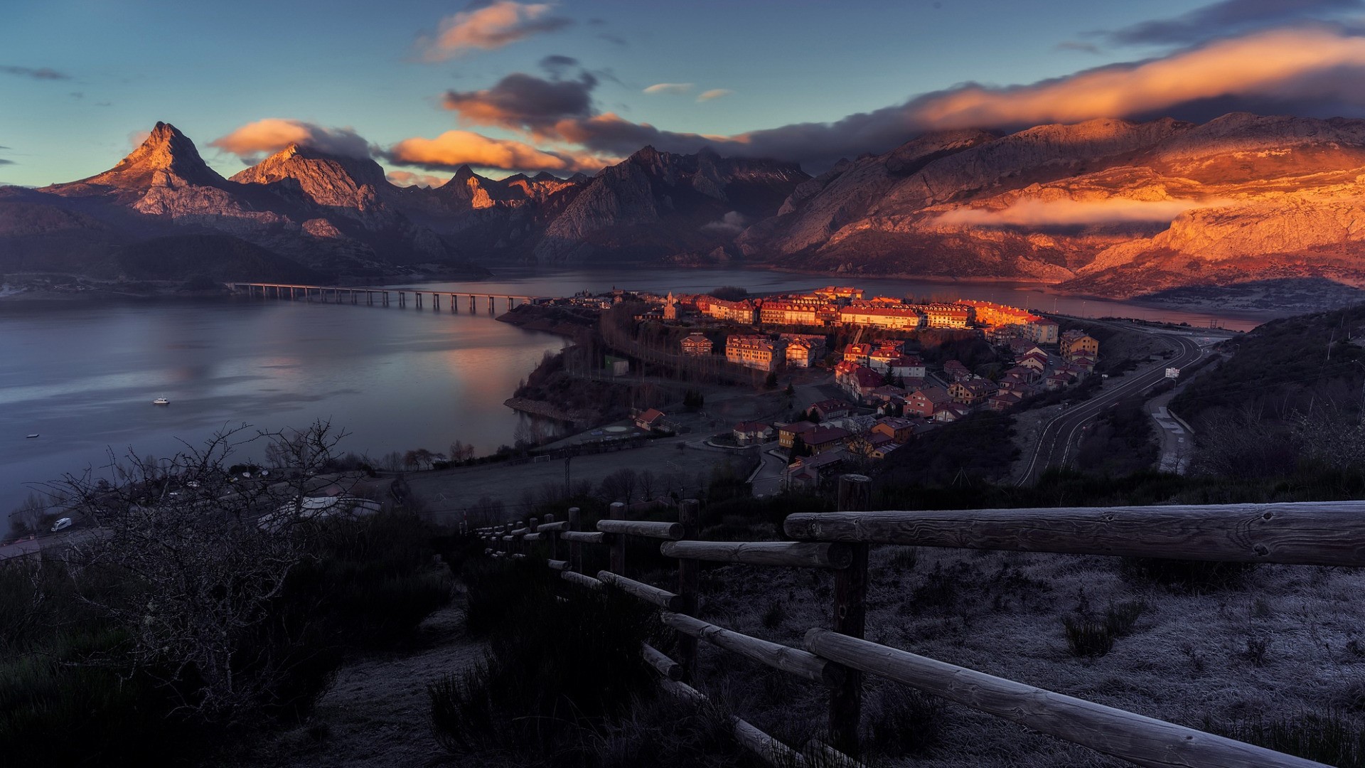 Sunset over a town and bay with mountains and a bridge HD Wallpaper