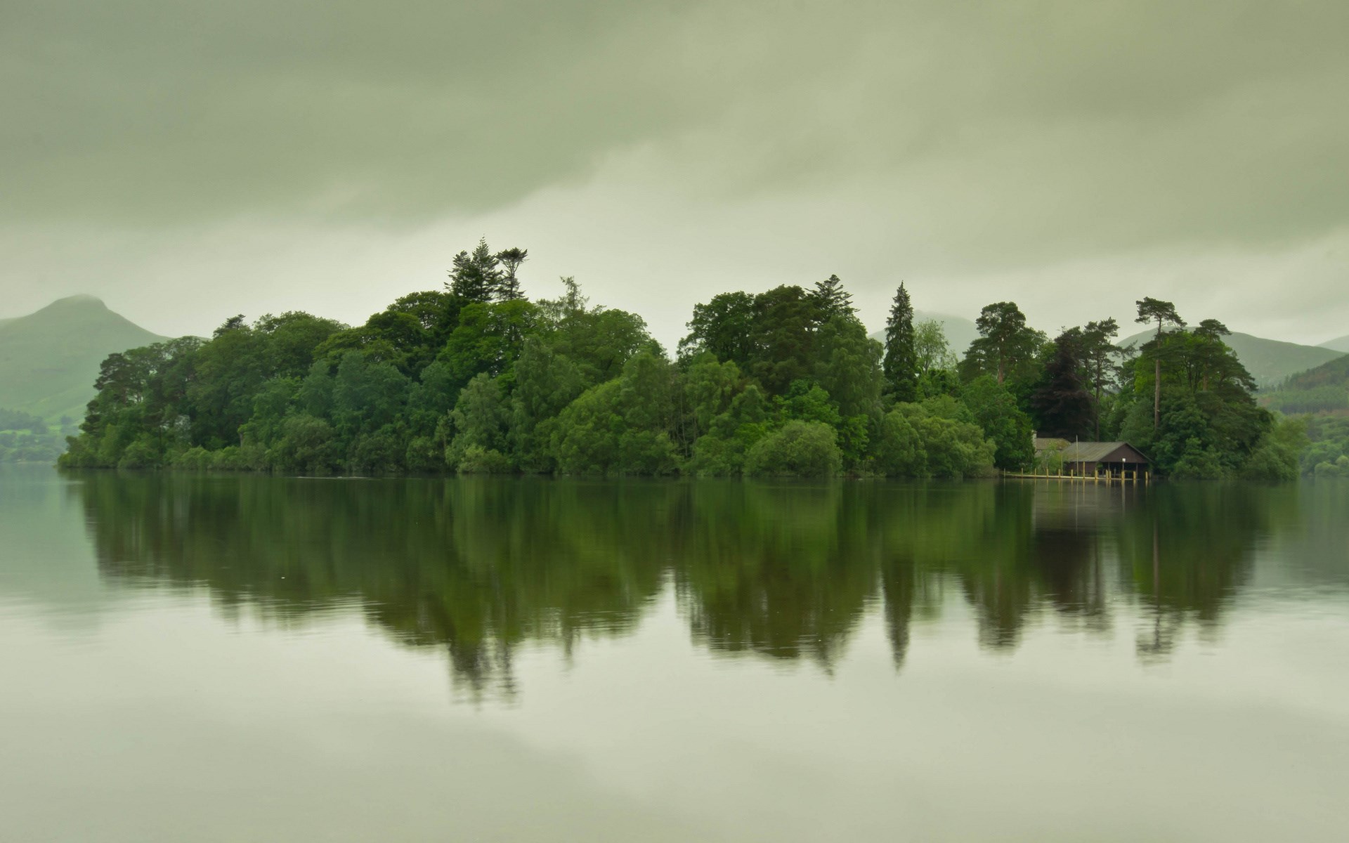 Island with trees and a boathouse on a lake HD Wallpaper