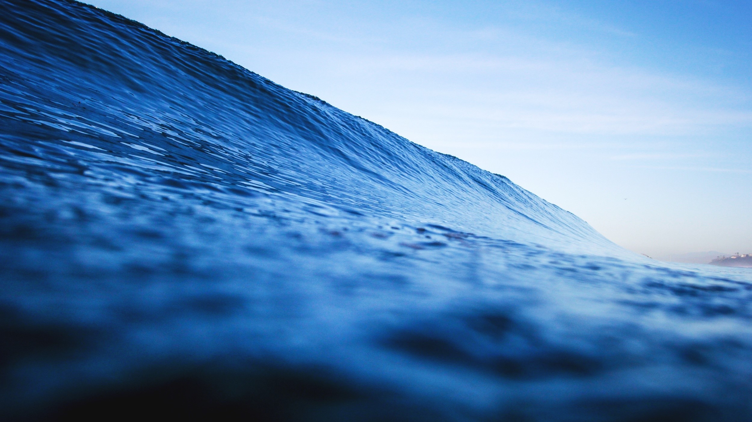 Ocean wave cresting under a clear blue sky HD Wallpaper
