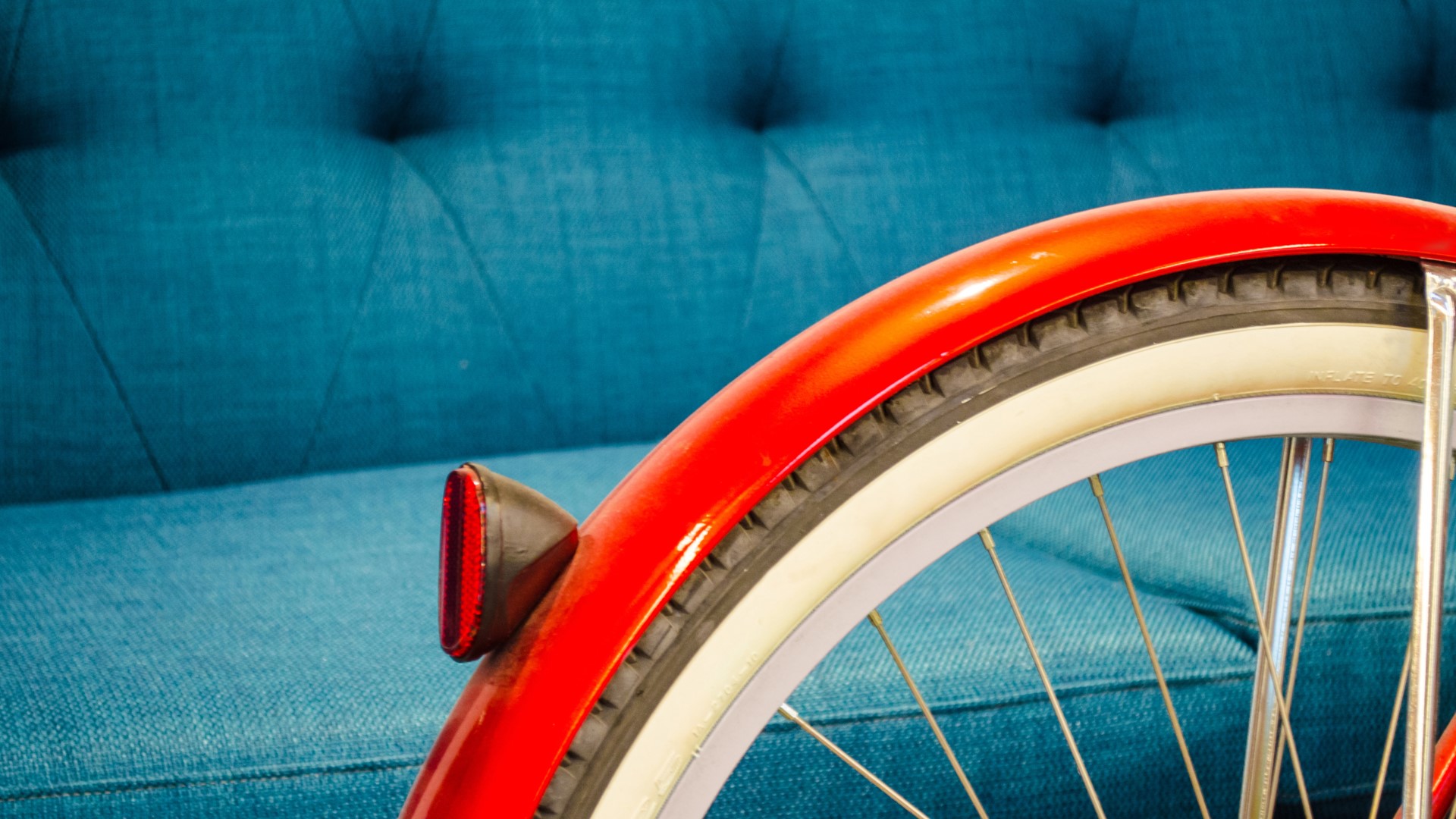 Red bicycle fender and wheel on blue couch HD Wallpaper