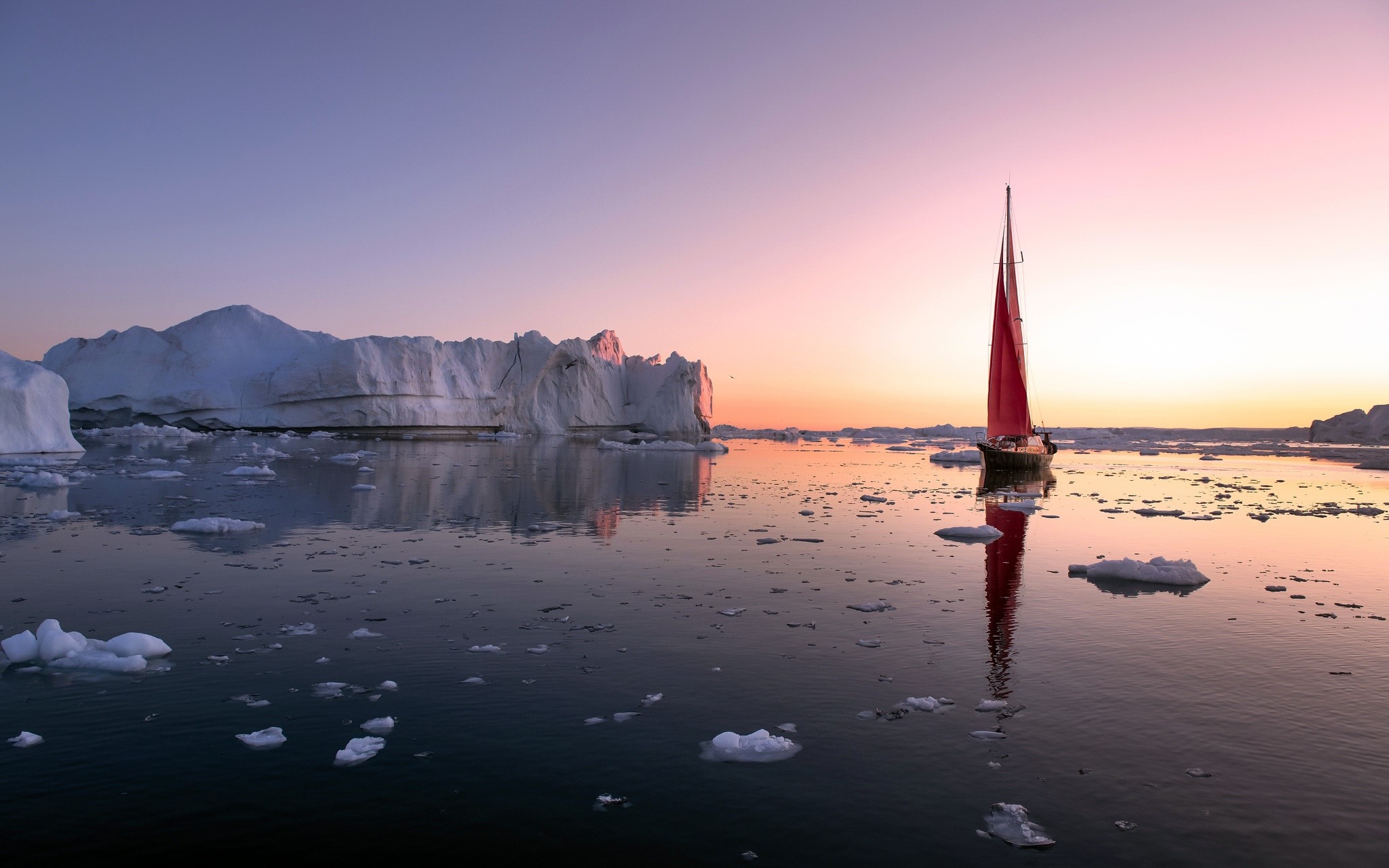 Sailboat with red sail among icebergs at sunset HD Wallpaper