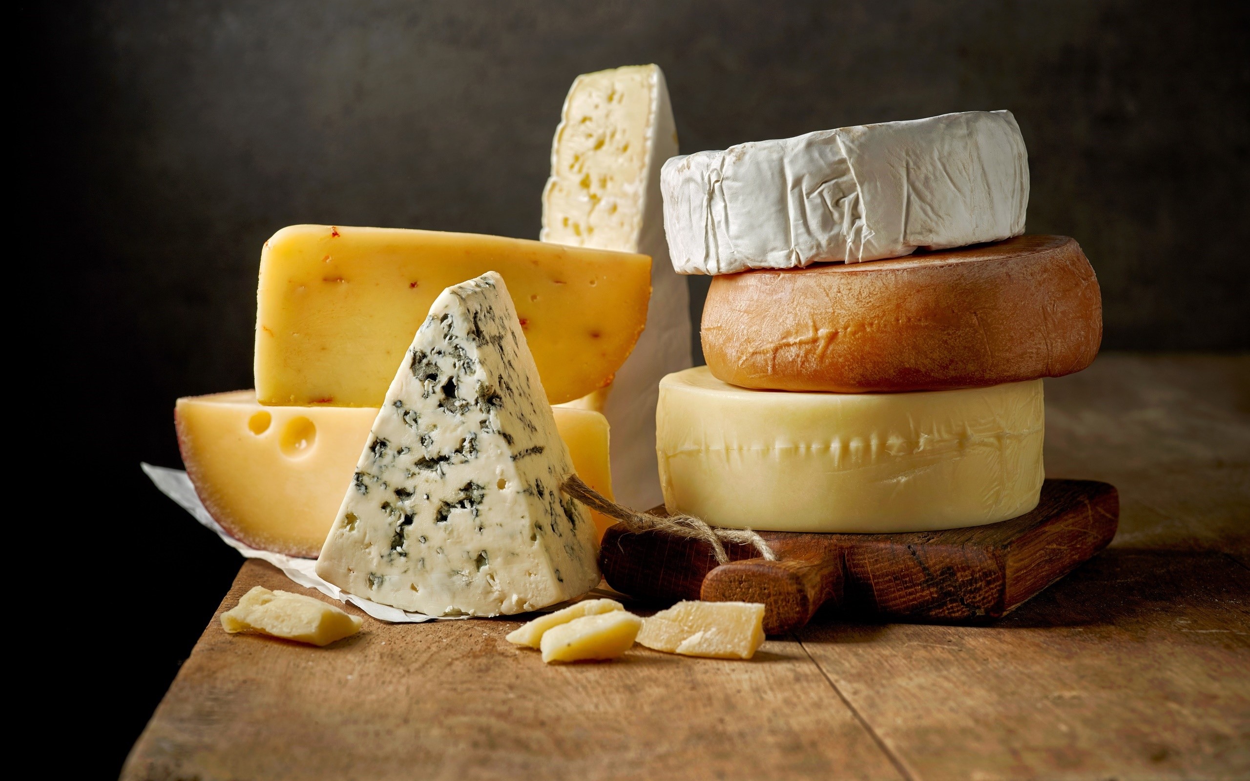 Assortment of cheeses on a wooden surface HD Wallpaper