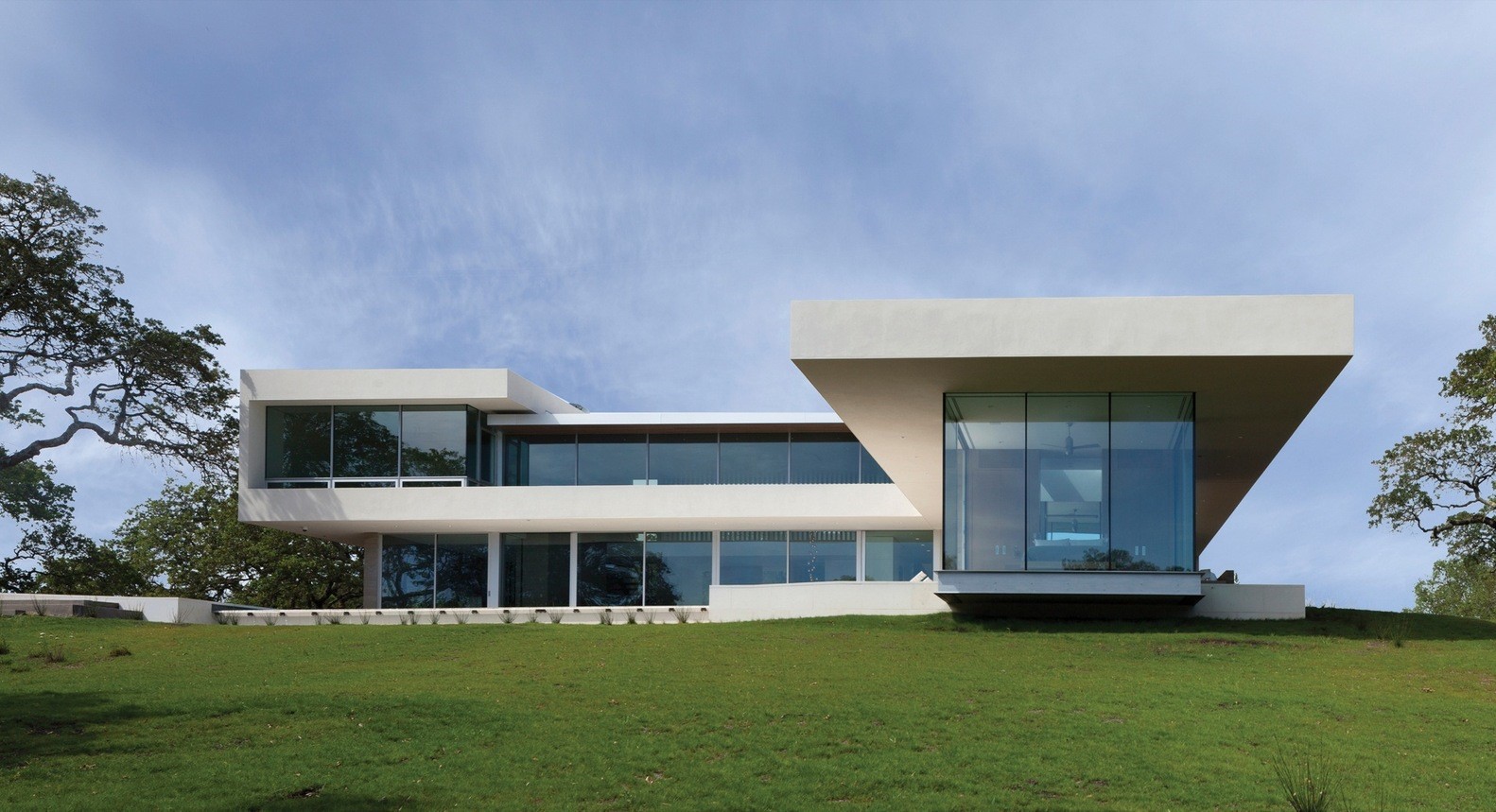 Modern mansion with large windows on a grassy hill HD Wallpaper