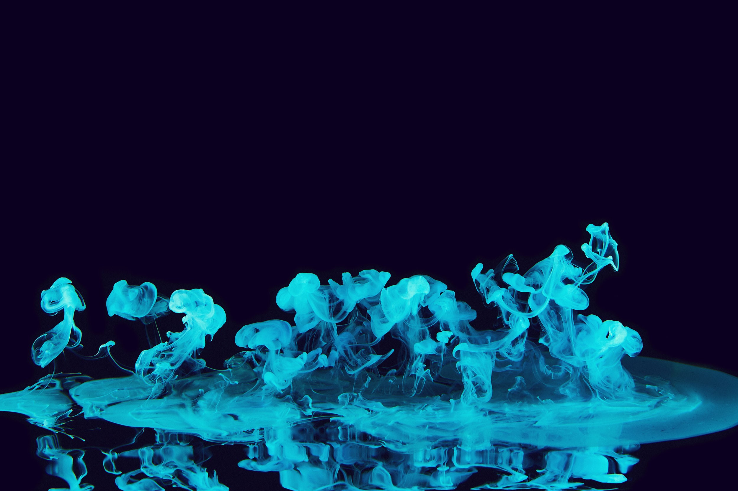 Cyan ink dissolving in water against a dark background HD Wallpaper
