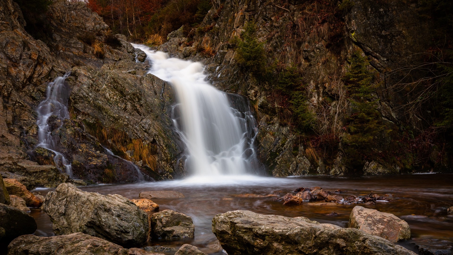 Waterfall cascading over rocks in a forest HD Wallpaper