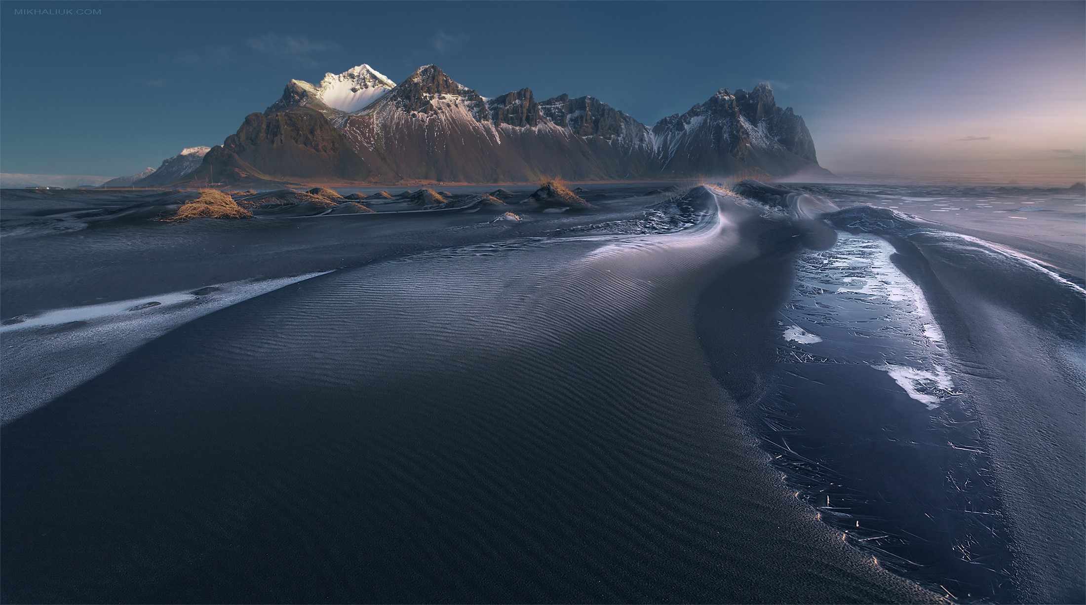 Snow-capped mountains over black sand dunes HD Wallpaper
