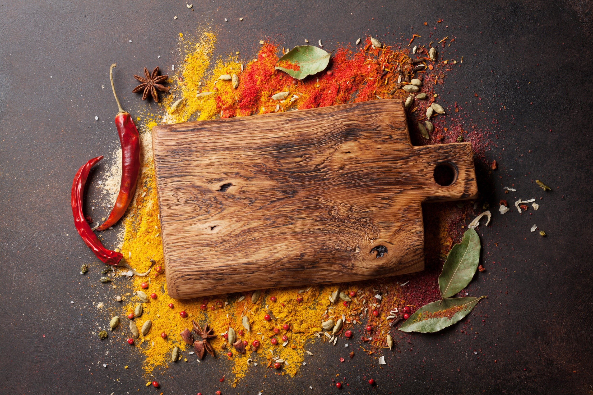 Wooden cutting board with colorful spices and chili peppers HD Wallpaper
