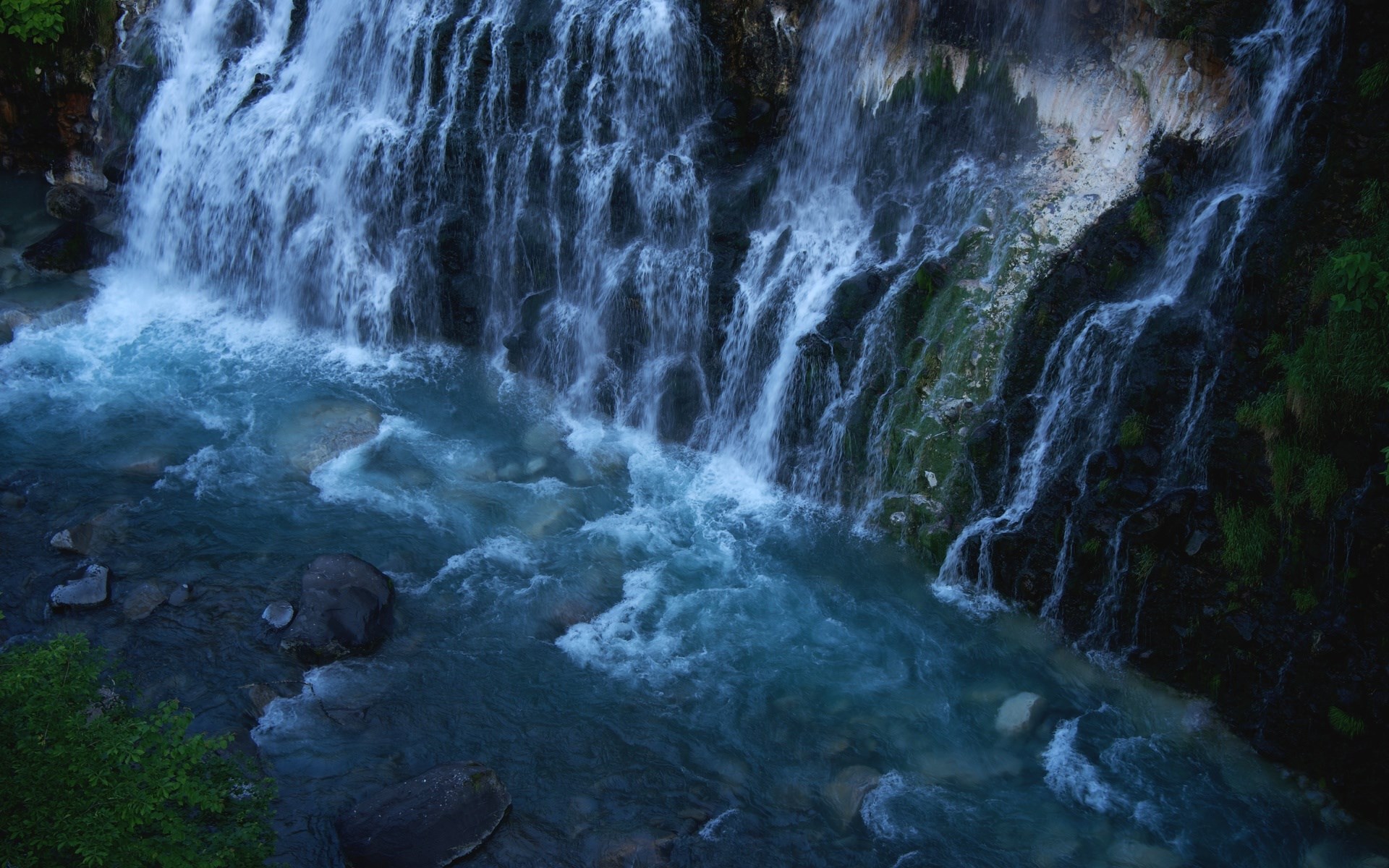 Waterfall cascading into a turquoise river HD Wallpaper