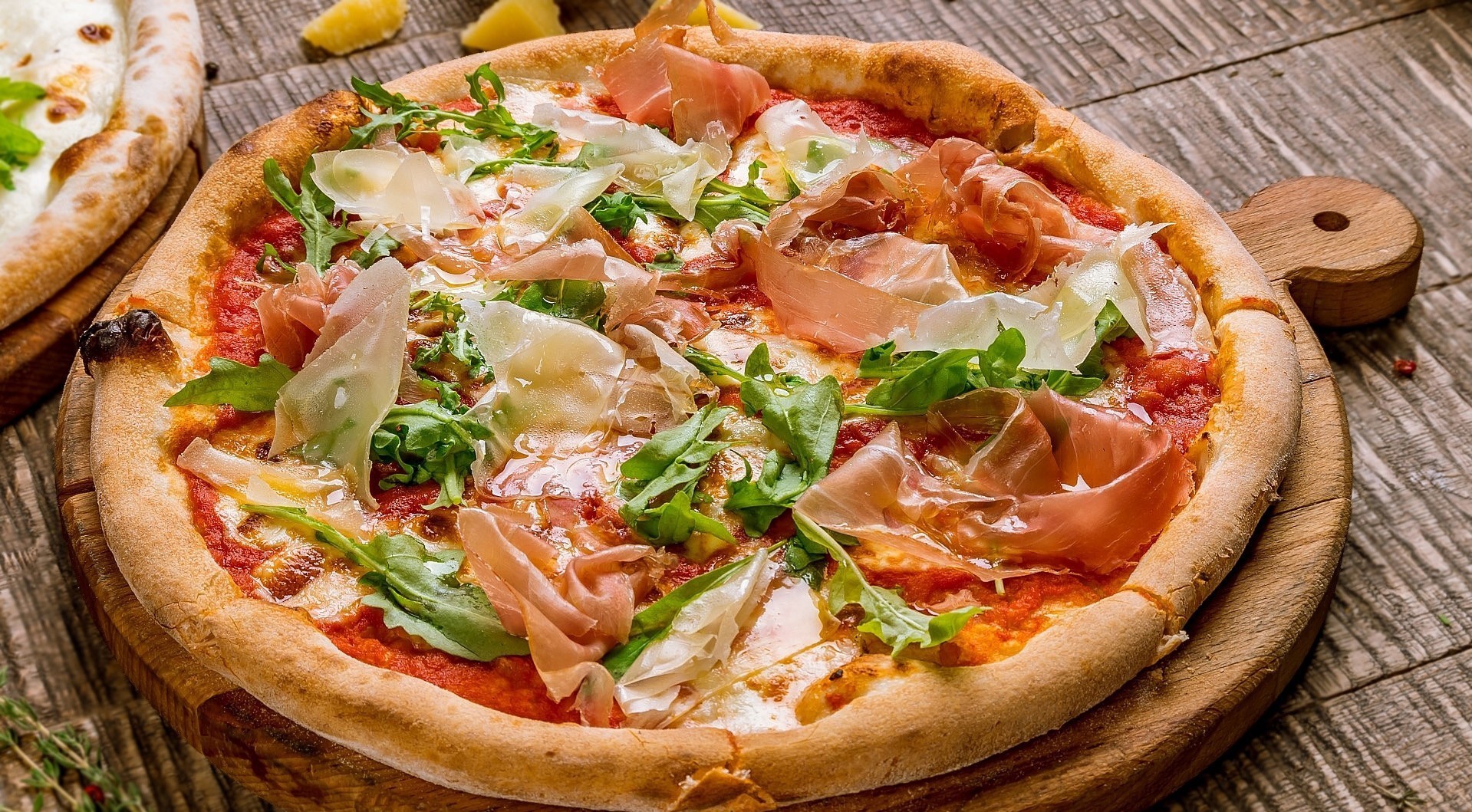 Pizza with prosciutto and arugula on a wooden board HD Wallpaper