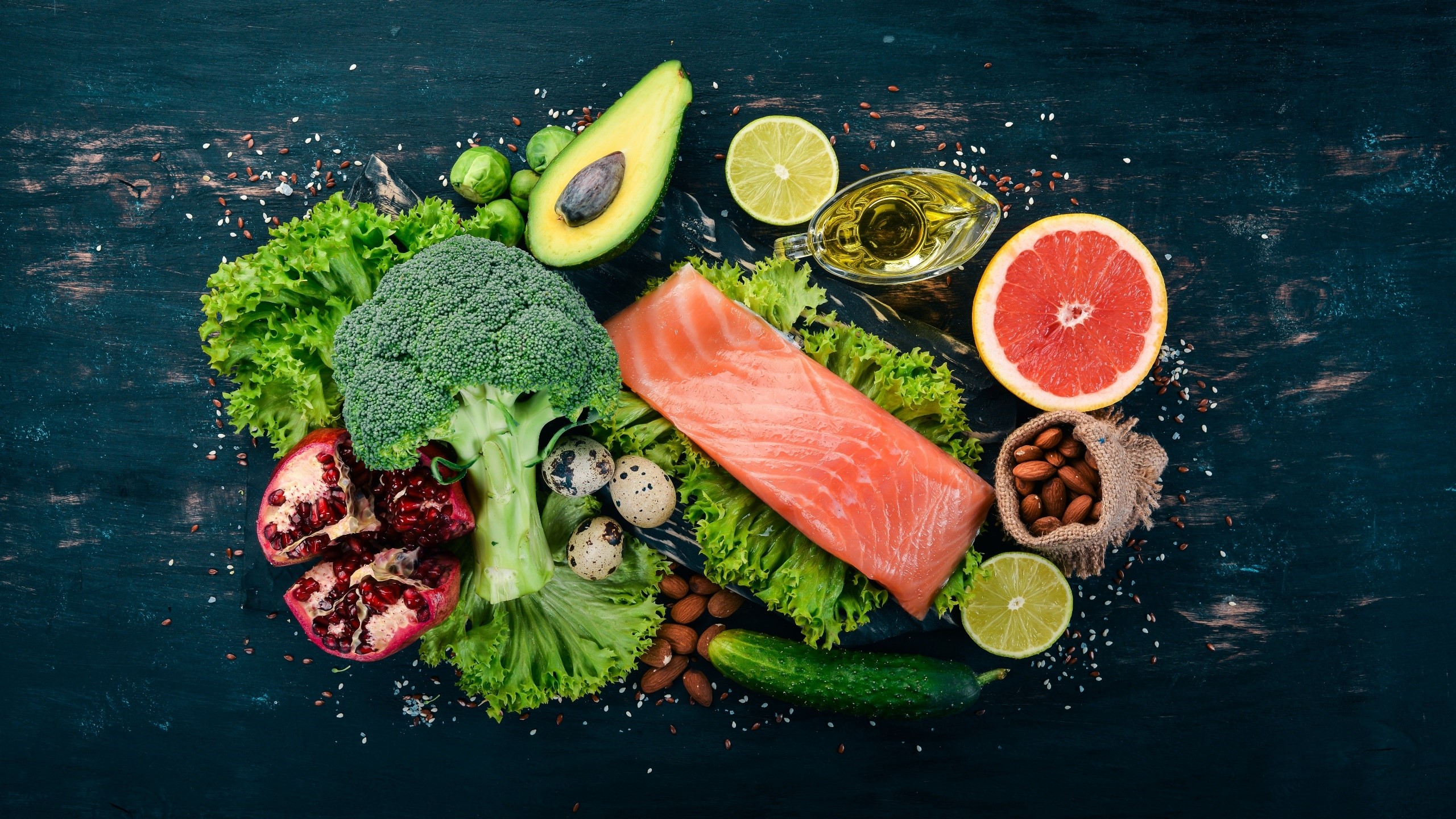 Salmon, vegetables, fruits, nuts, and olive oil on dark wood HD Wallpaper