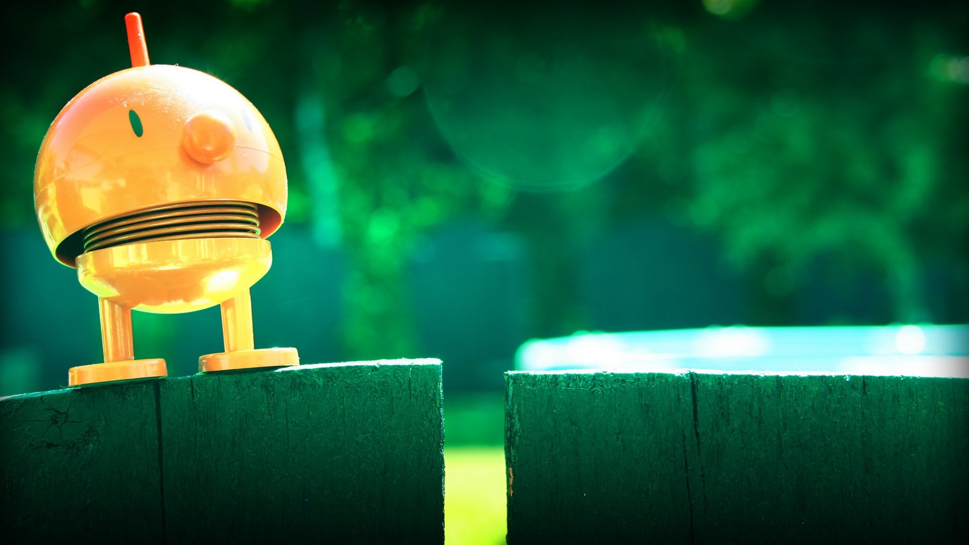 Orange toy robot on a wooden fence HD Wallpaper