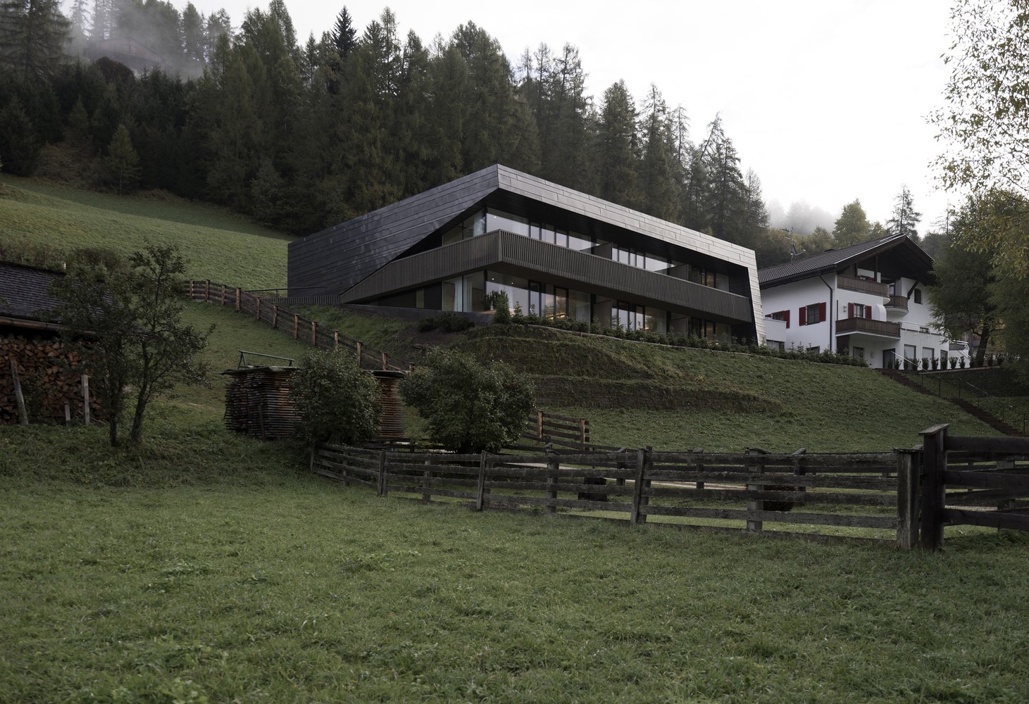 Modern house on a grassy hillside with a forest background HD Wallpaper