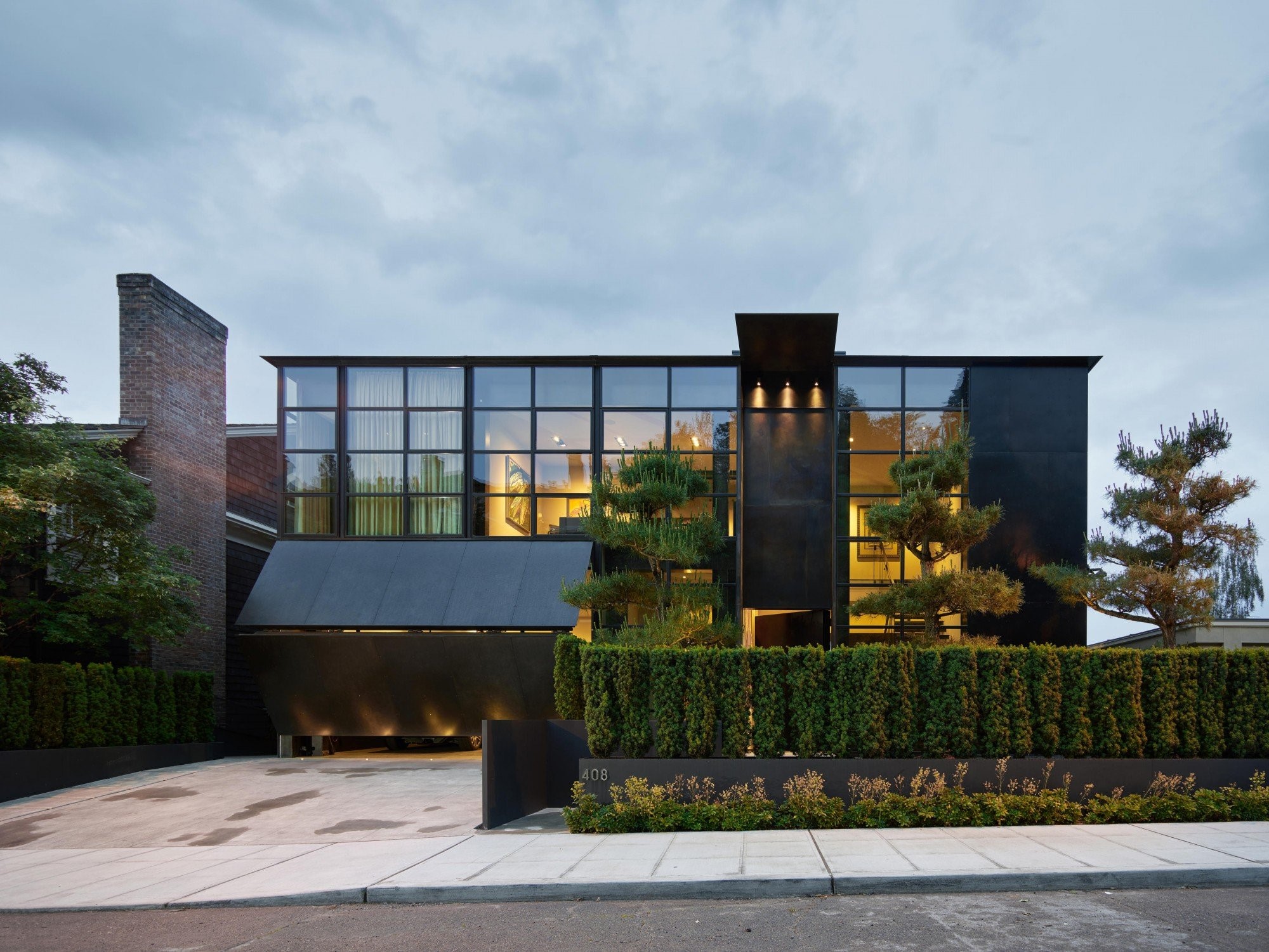 Modern black house with large windows and hedge HD Wallpaper