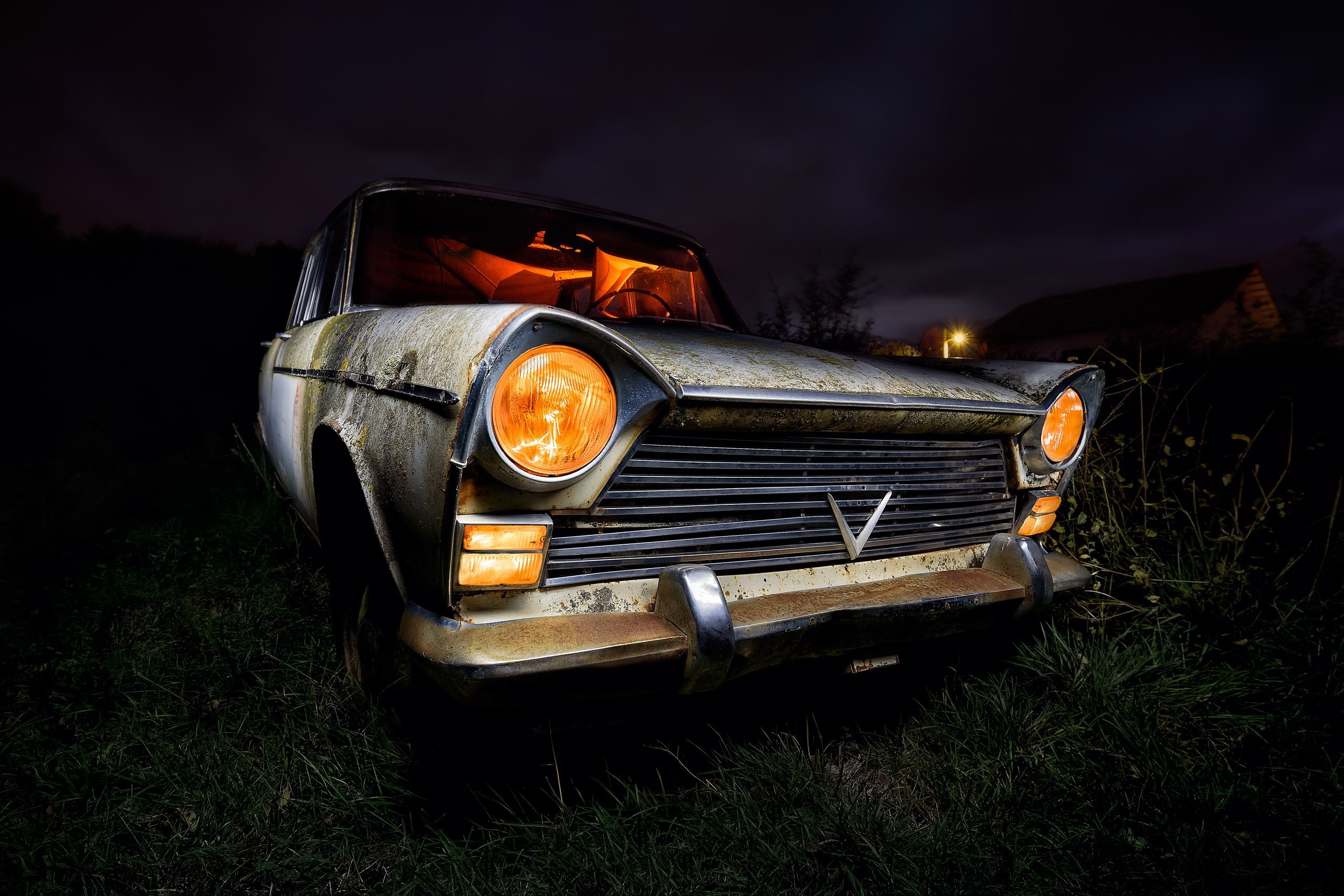 Old rusty car with glowing headlights at night HD Wallpaper