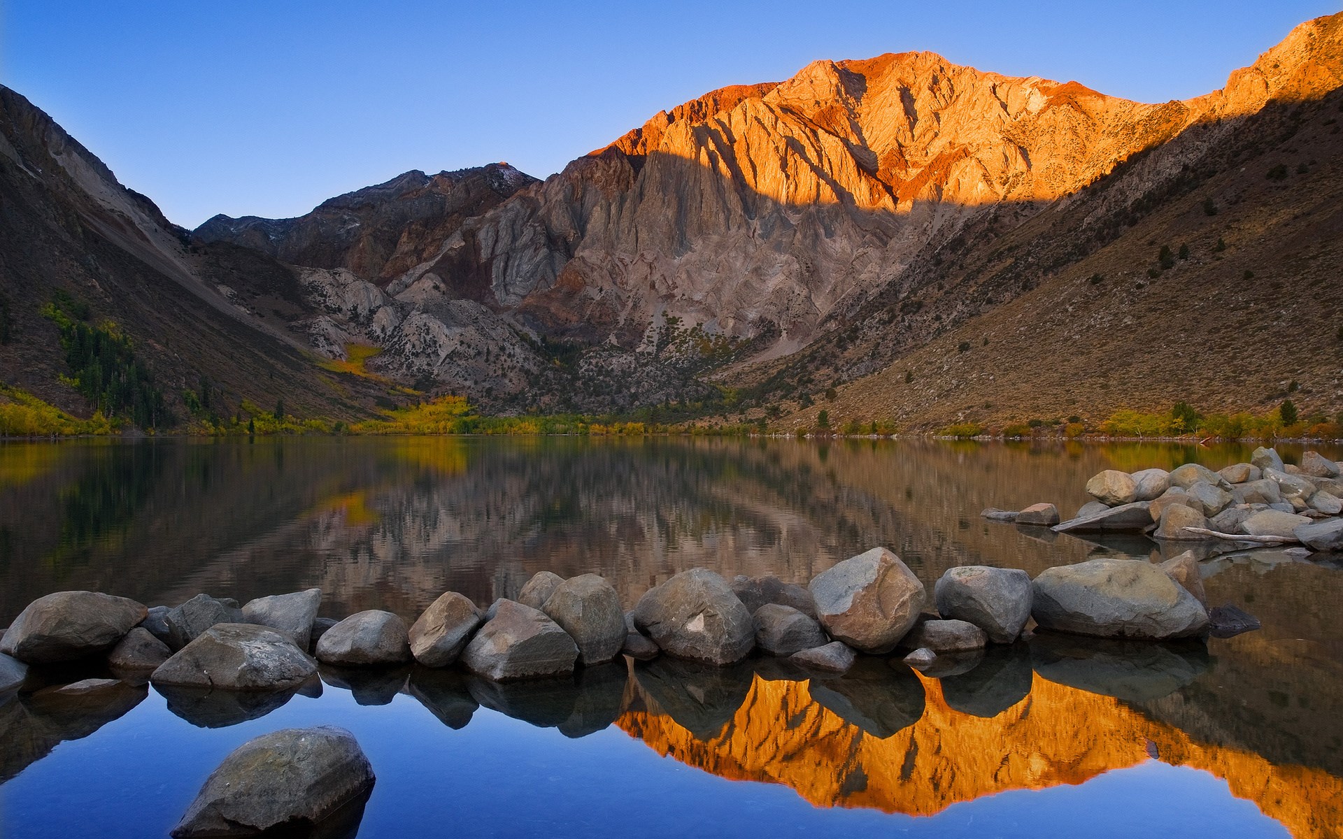 Mountain lake at sunrise with rocks in foreground HD Wallpaper
