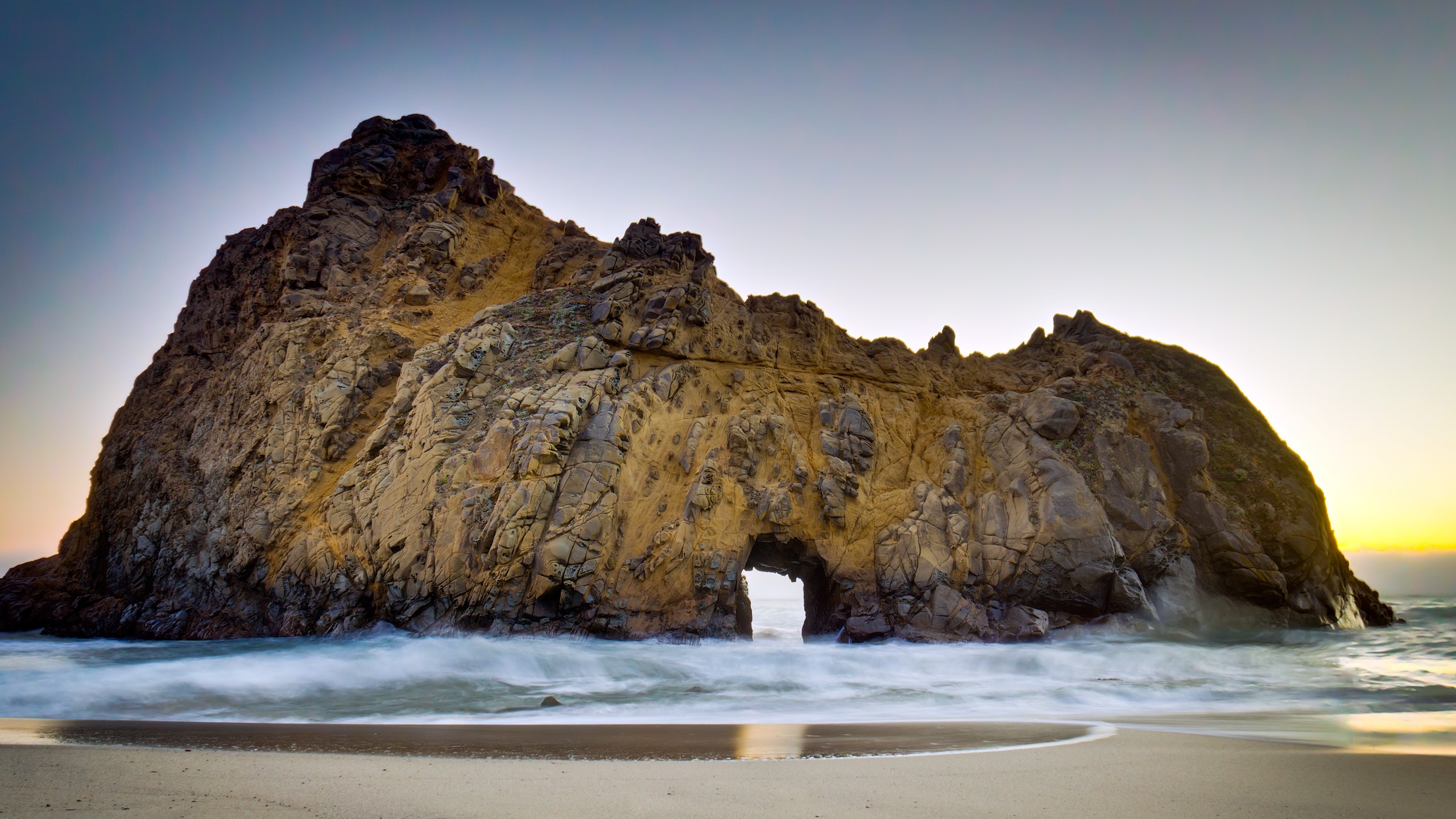 Rock formation with archway on a beach HD Wallpaper