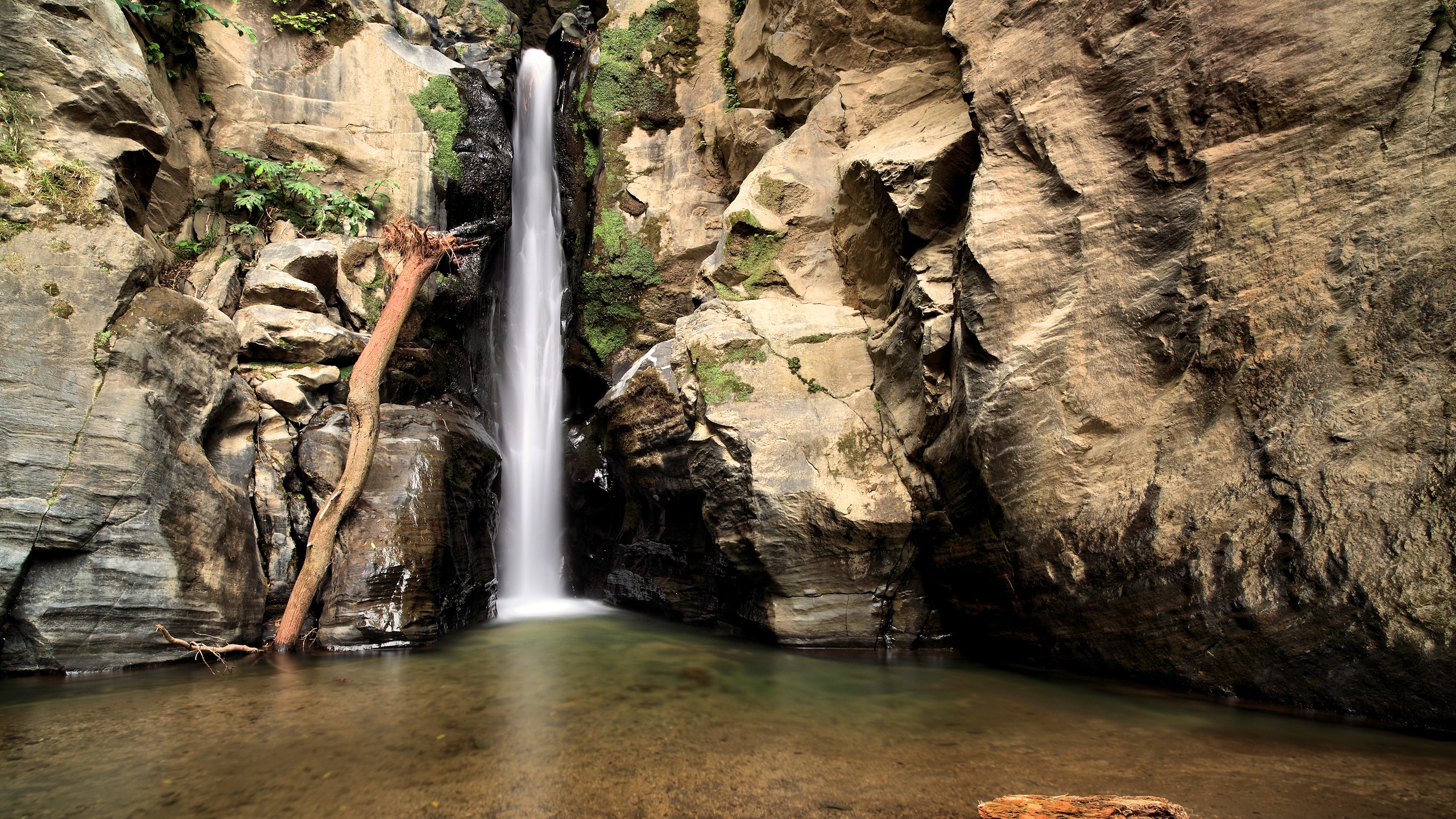 Waterfall cascading into a pool surrounded by rocks HD Wallpaper