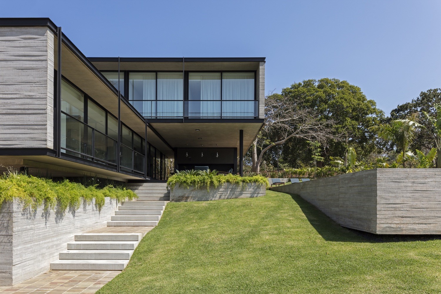 Modern concrete house with large windows and green lawn HD Wallpaper