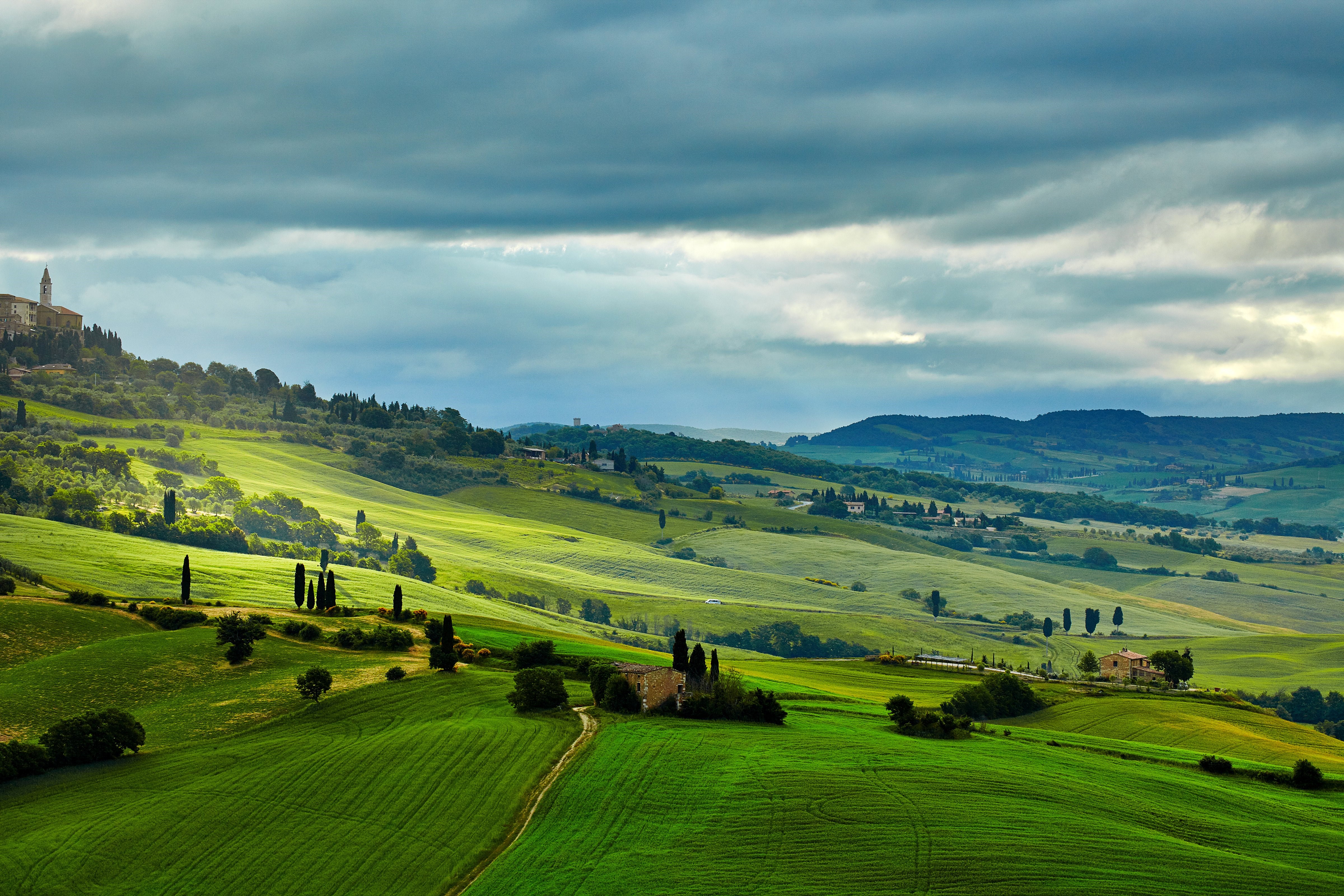 Tuscan landscape with rolling green hills and a village HD Wallpaper