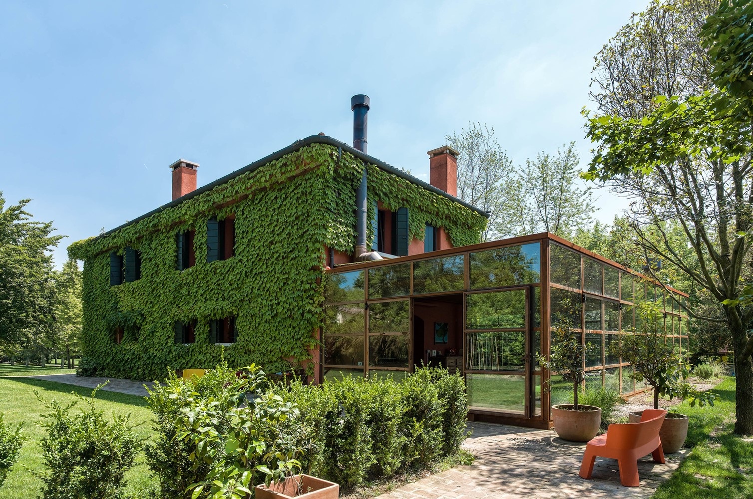 Ivy-covered house with glass conservatory and garden HD Wallpaper