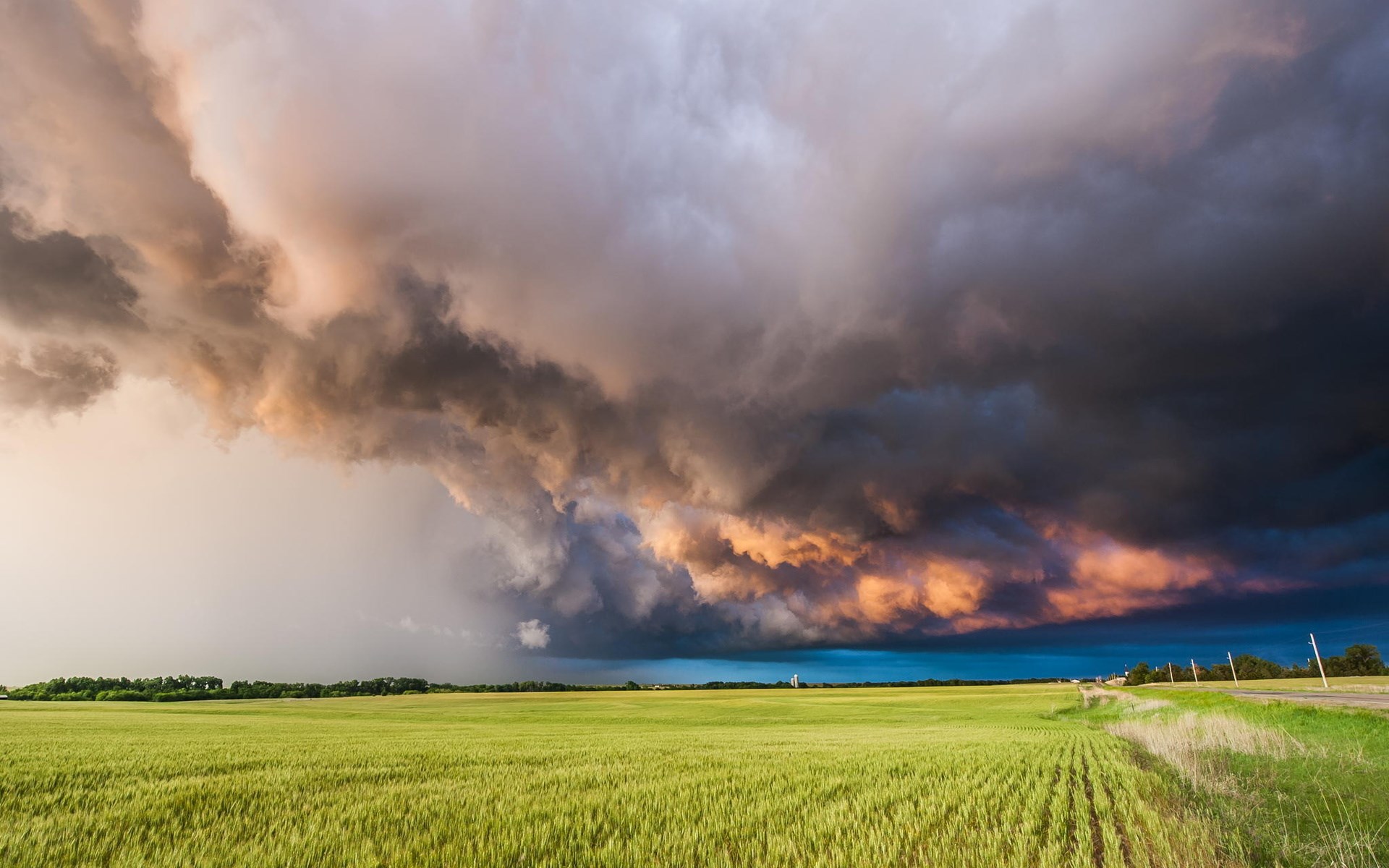Storm clouds over a green field HD Wallpaper