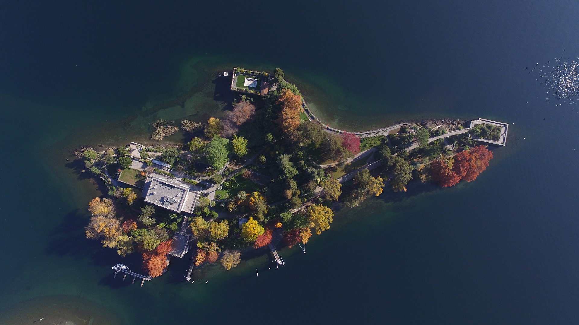 Aerial view of an island with buildings and trees in a lake HD Wallpaper