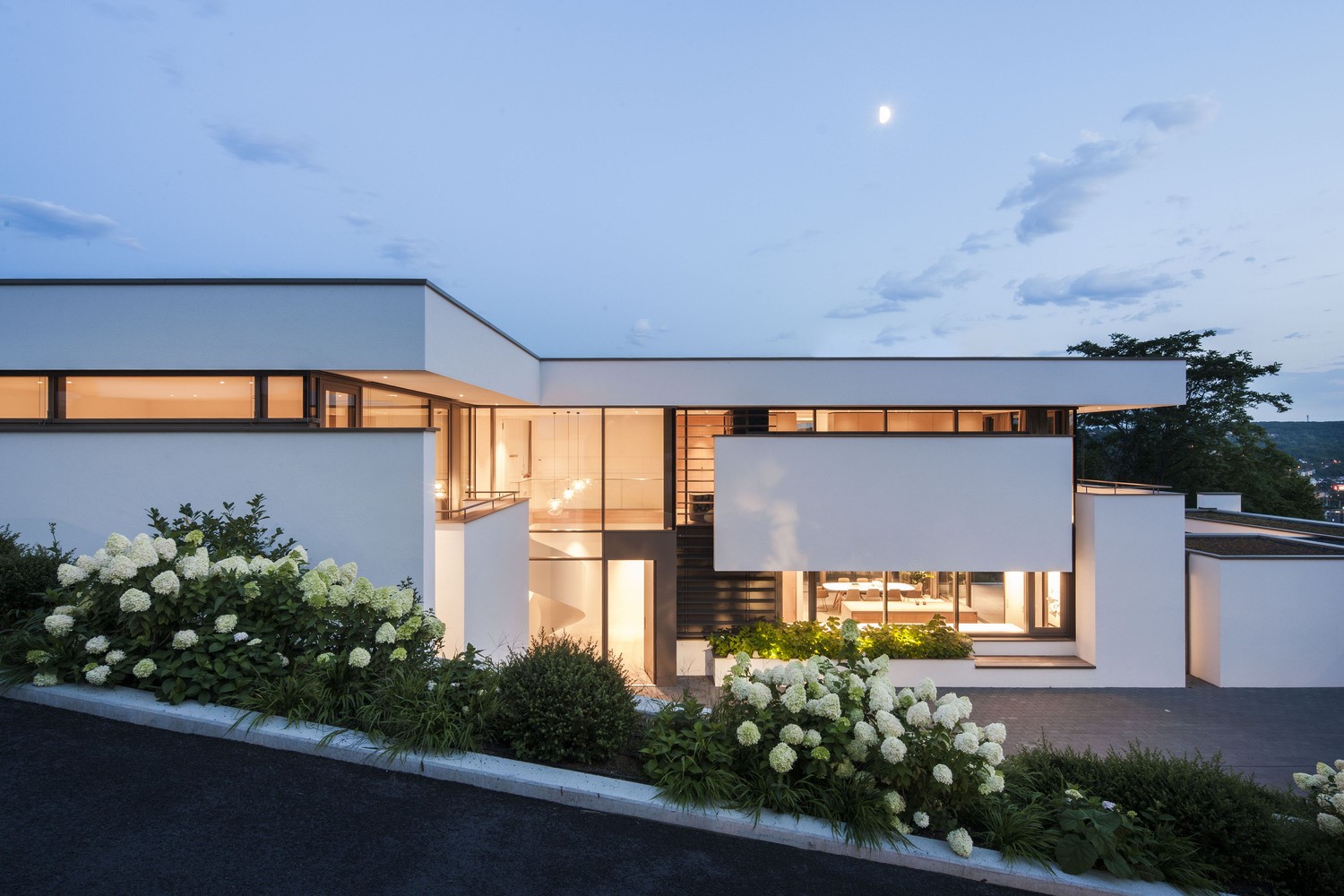 Modern white house with large windows and landscaping HD Wallpaper