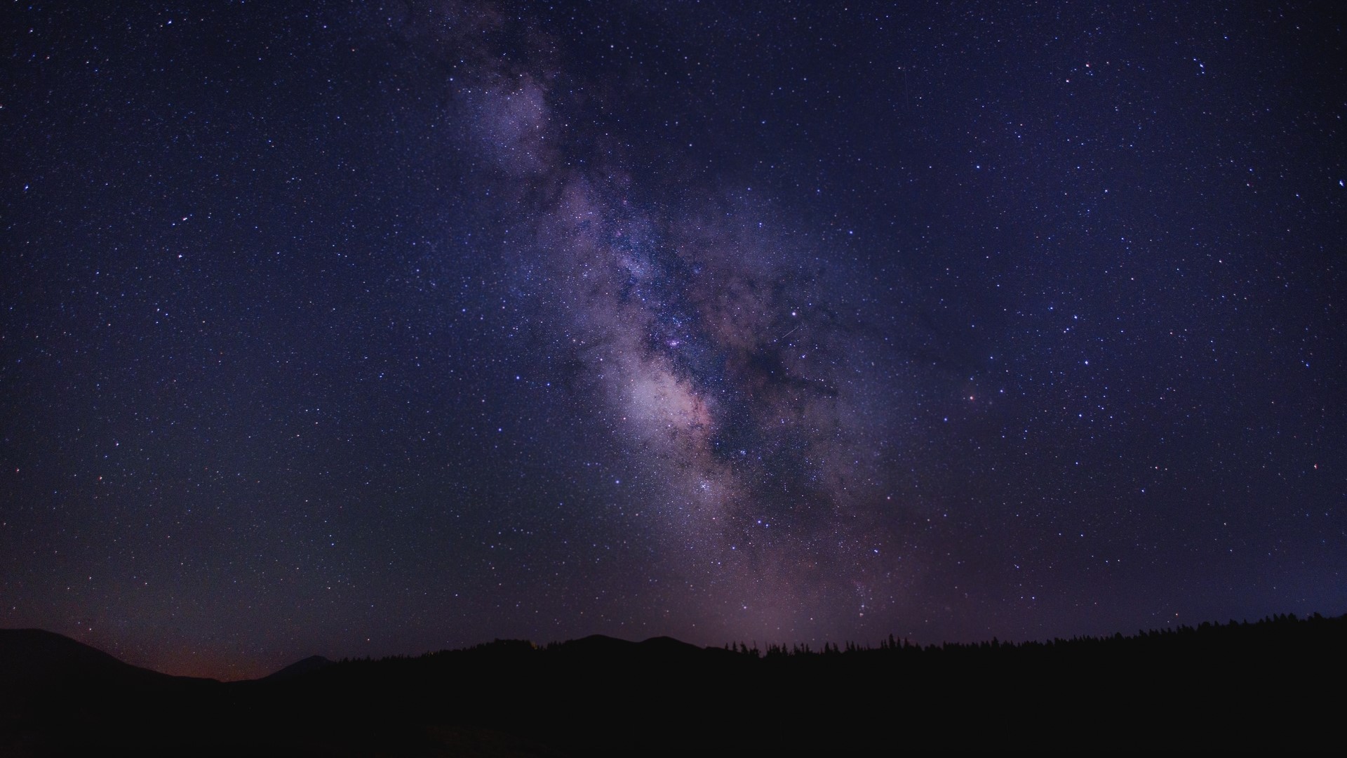 Milky Way galaxy over a silhouetted mountain range HD Wallpaper