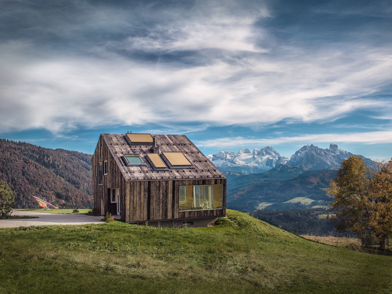 Modern wooden house on a grassy hill with mountains HD Wallpaper