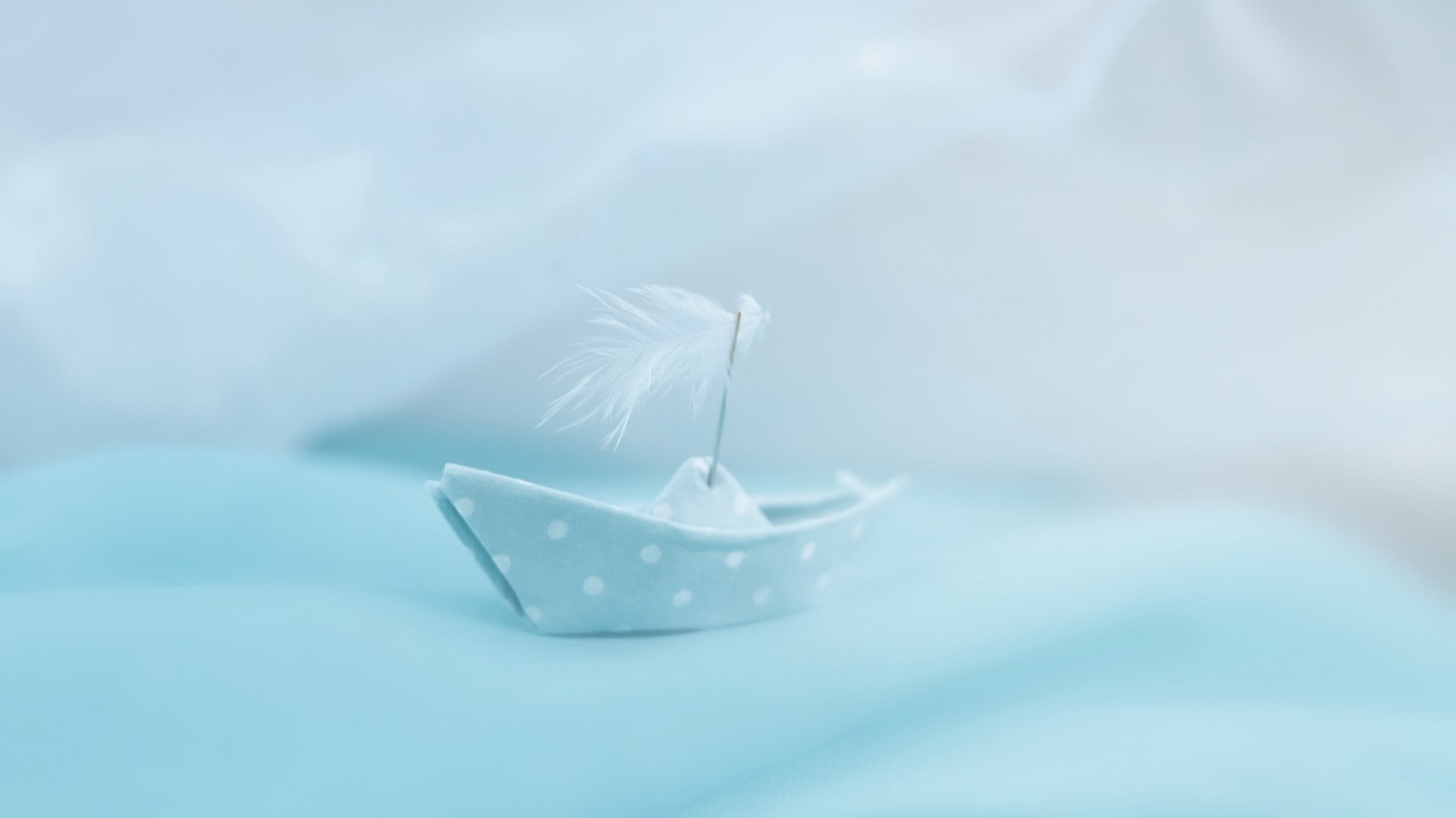 A small blue polka dot paper boat with a feather sail HD Wallpaper