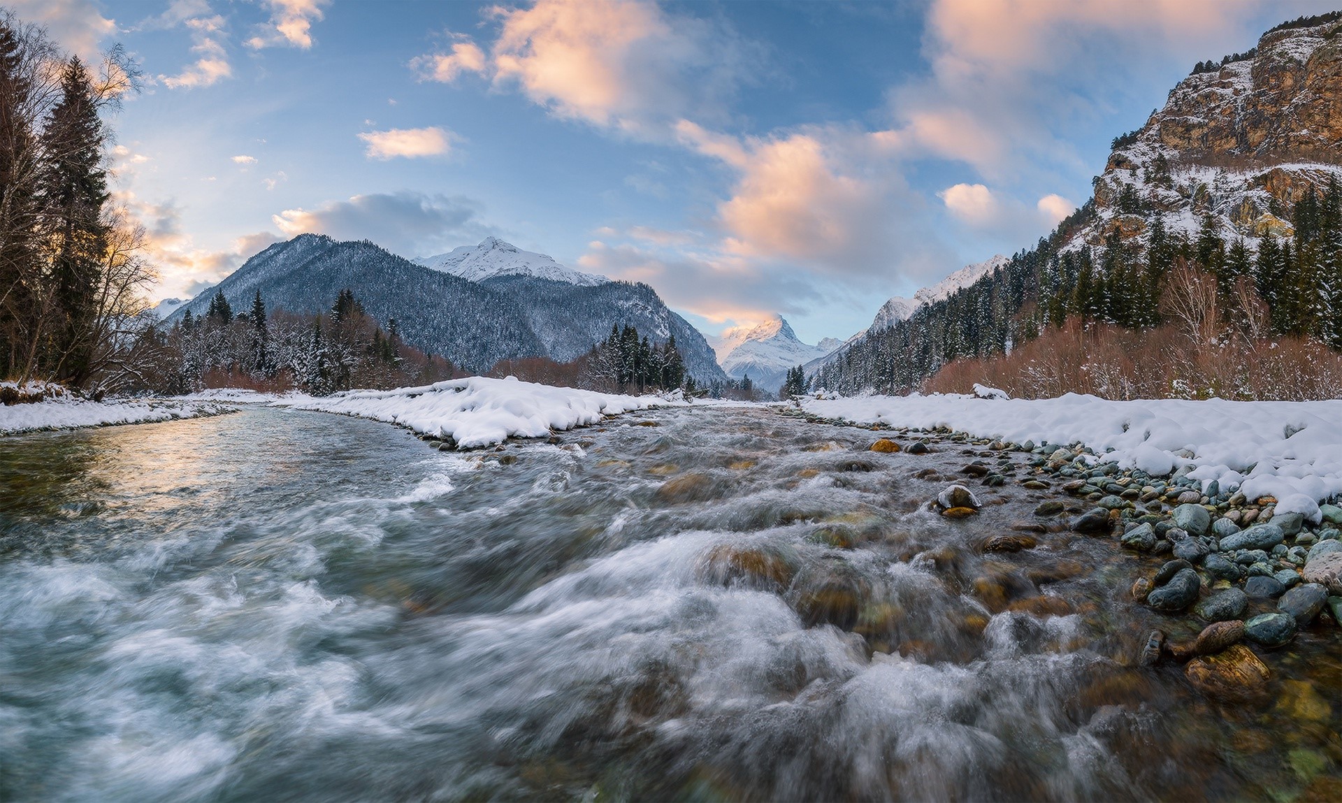 River flowing through a snowy mountain landscape at sunset HD Wallpaper