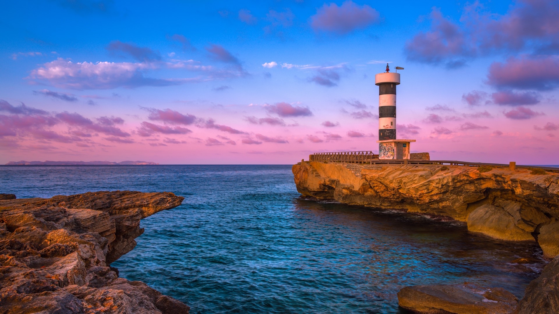Lighthouse on rocky coast at sunset, Spain HD Wallpaper