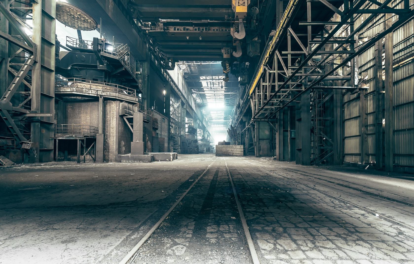 Interior of a large, abandoned industrial factory with train tracks HD Wallpaper