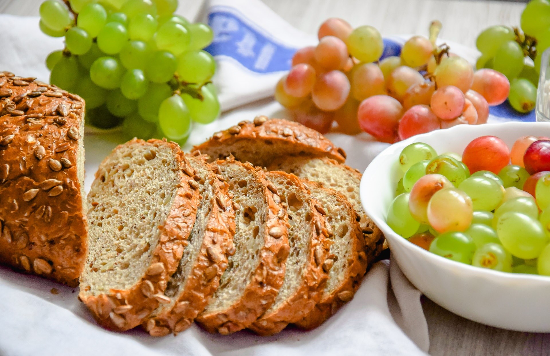 Sliced bread and grapes on a table HD Wallpaper