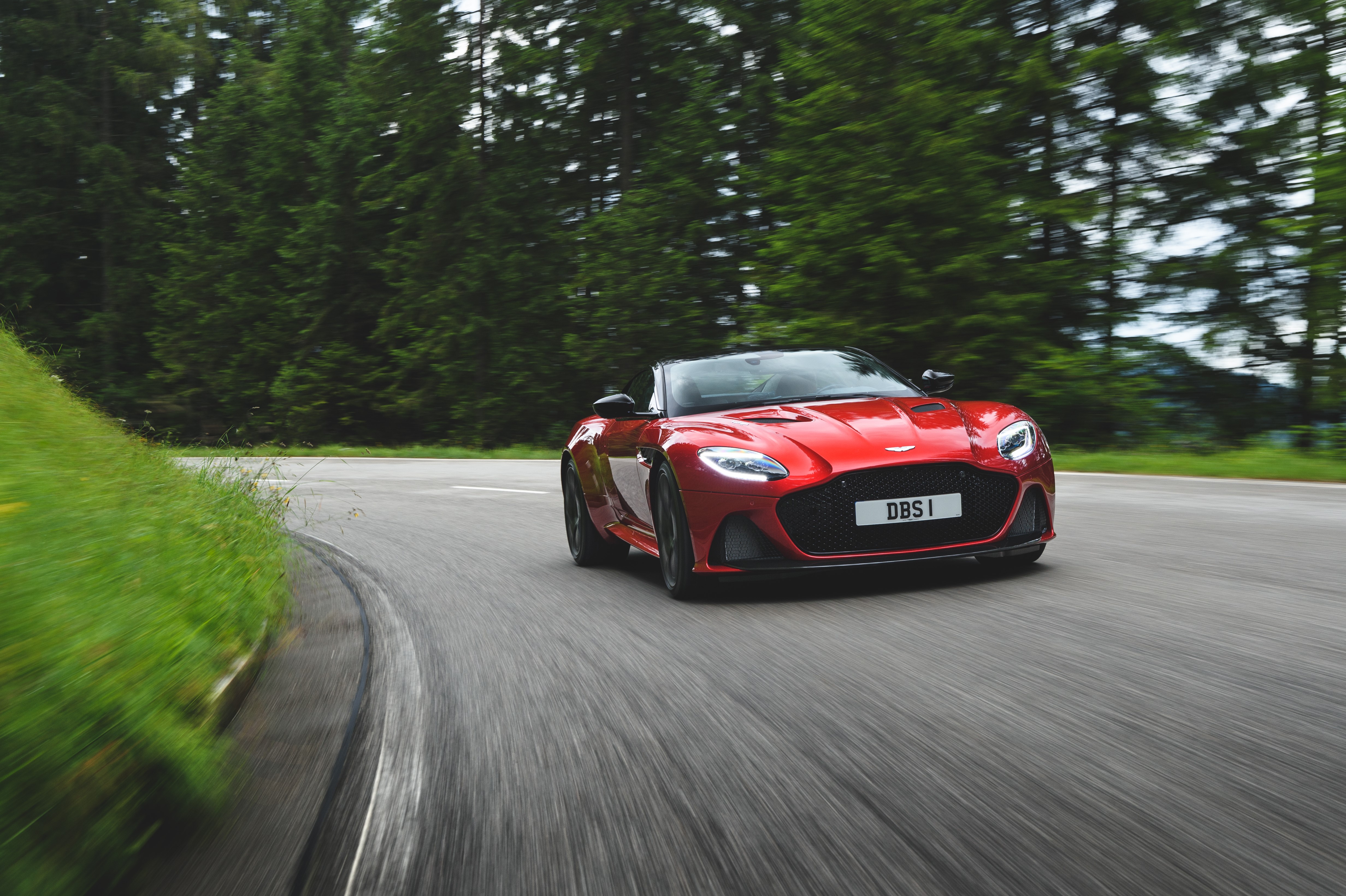 Red Aston Martin DBS Superleggera driving on a road HD Wallpaper