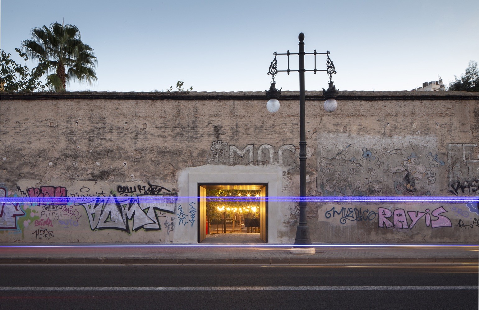Graffiti-covered wall with an illuminated entrance and street lamp HD Wallpaper