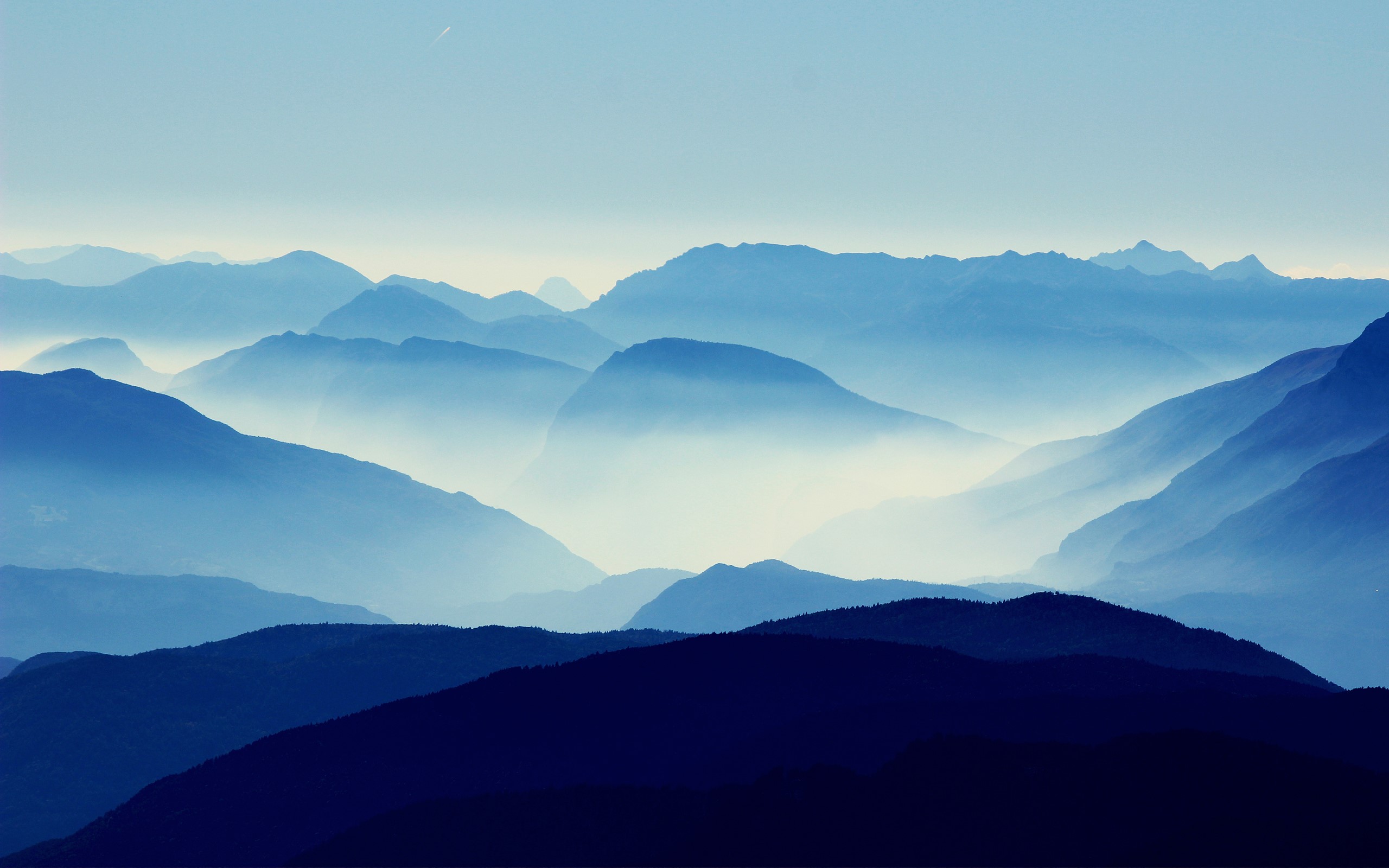 Blue mountains shrouded in mist under a clear sky HD Wallpaper
