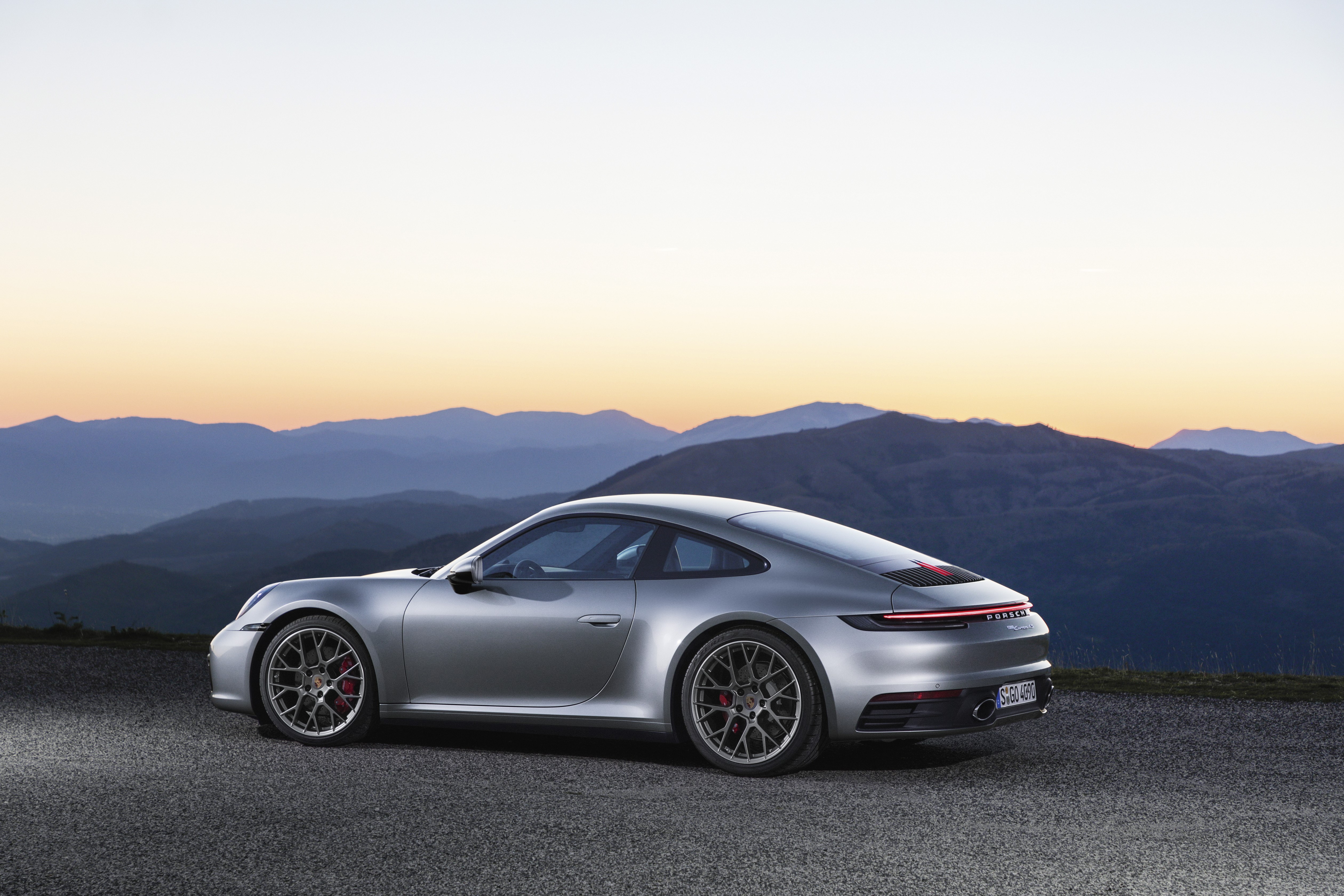 Silver Porsche 911 sports car on mountain road at sunset HD Wallpaper