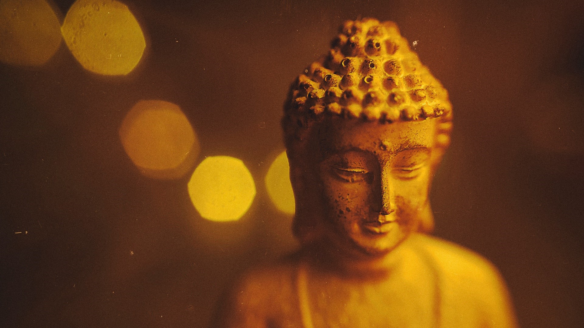 Close-up of a golden Buddha statue with bokeh lights HD Wallpaper