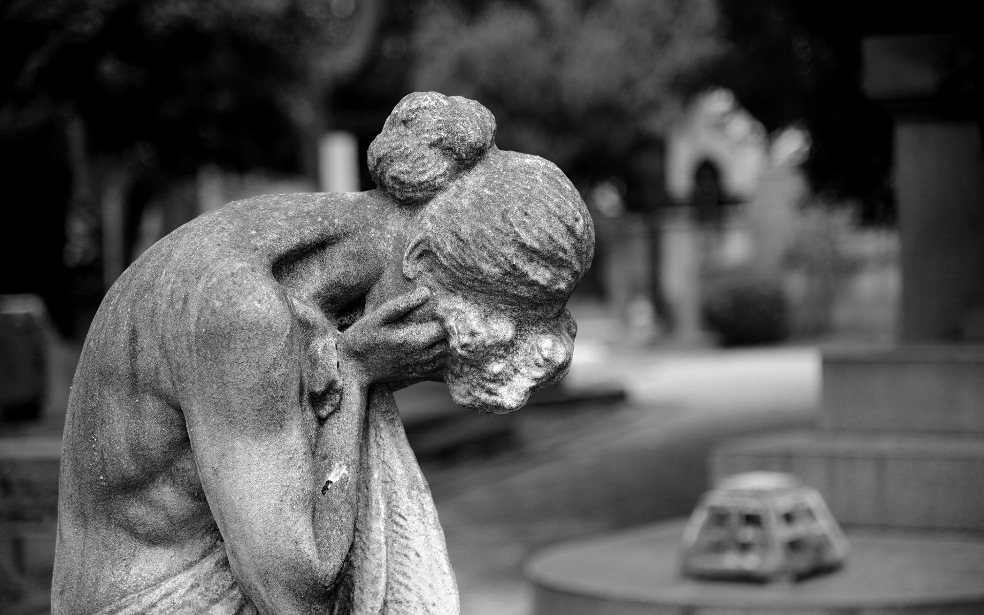 Monochrome statue of a grieving woman in a cemetery HD Wallpaper