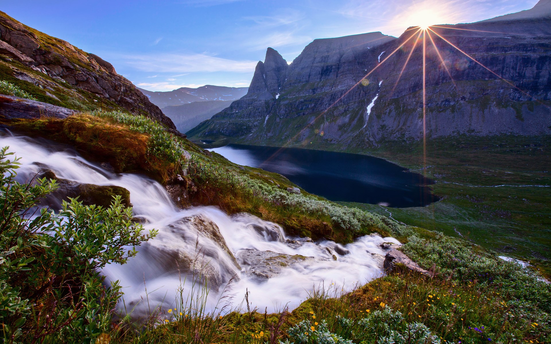 Waterfall flowing into a mountain lake with sunburst HD Wallpaper