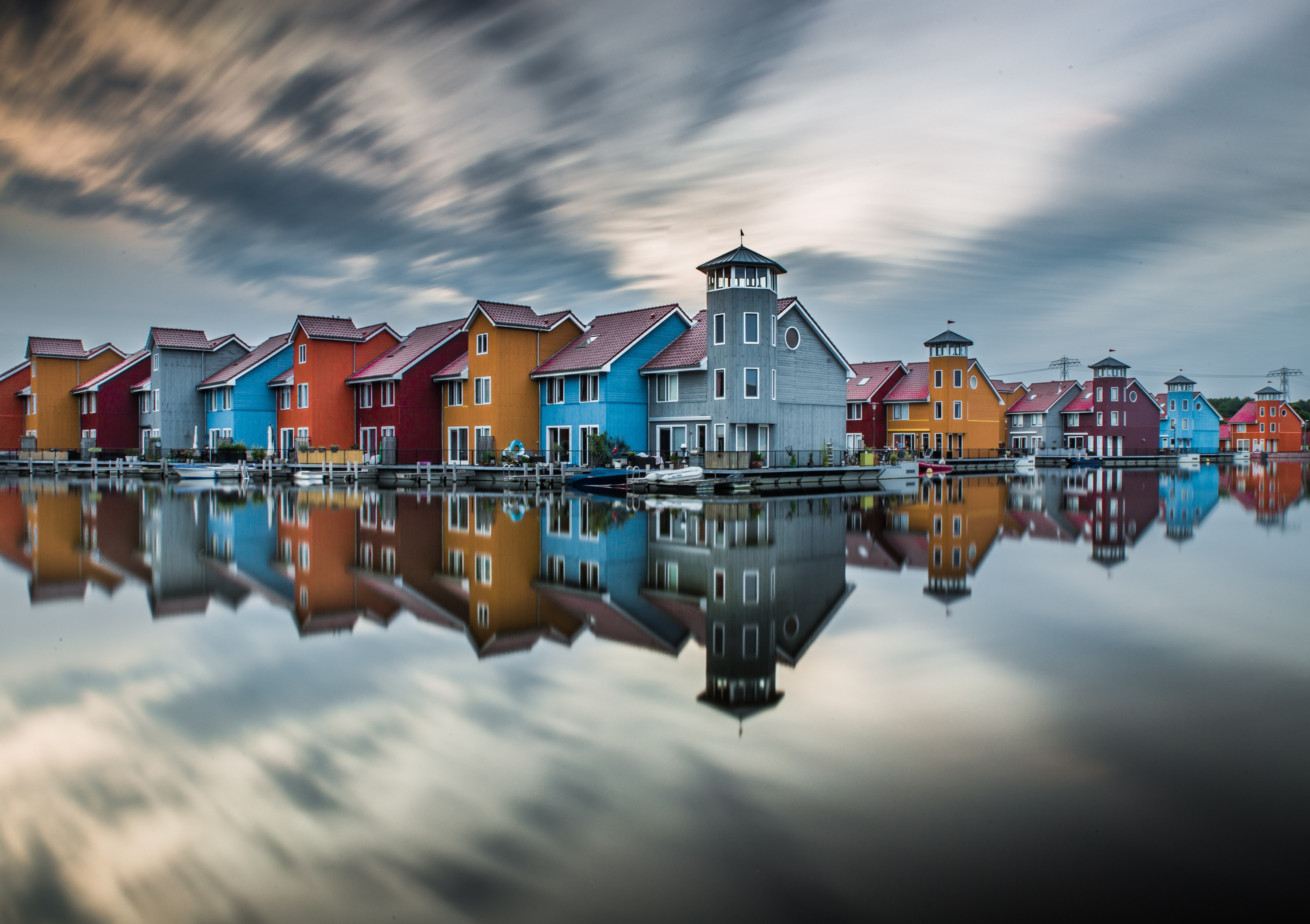 Colorful houses reflected in water with streaky clouds HD Wallpaper
