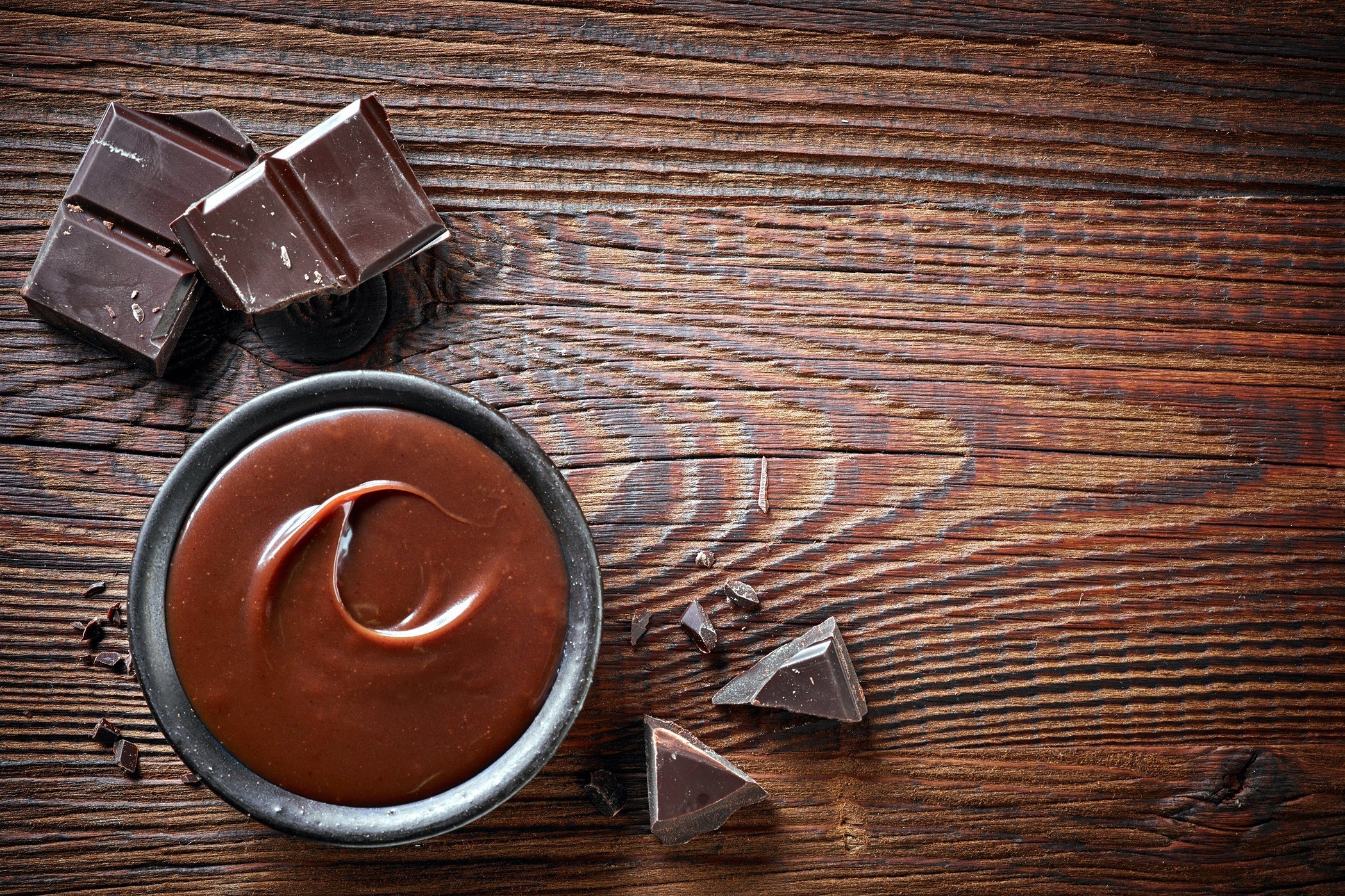 Melted chocolate in a bowl with chocolate bars on a wooden surface HD Wallpaper