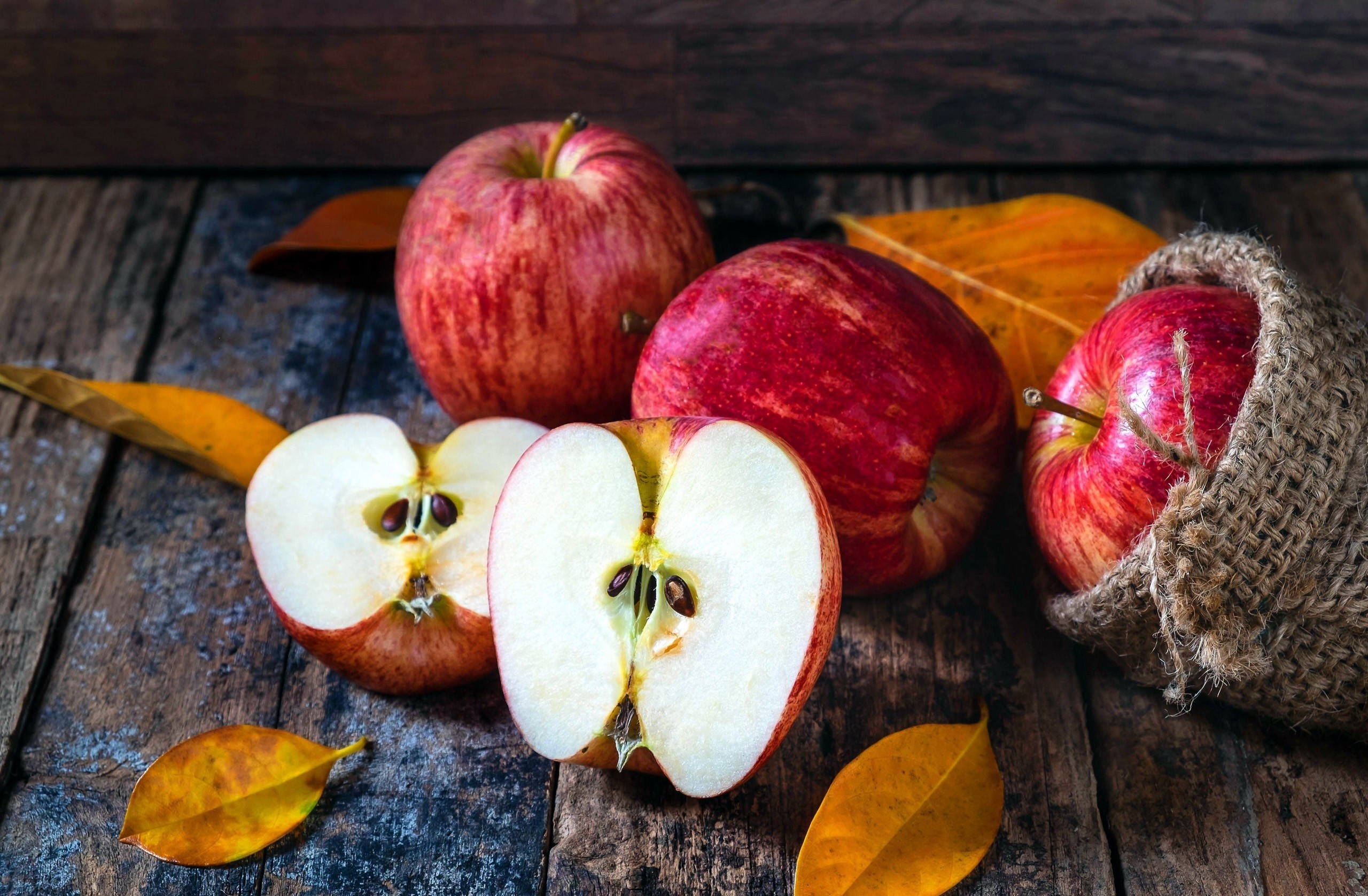 Still life of red apples and autumn leaves on a wooden table HD Wallpaper