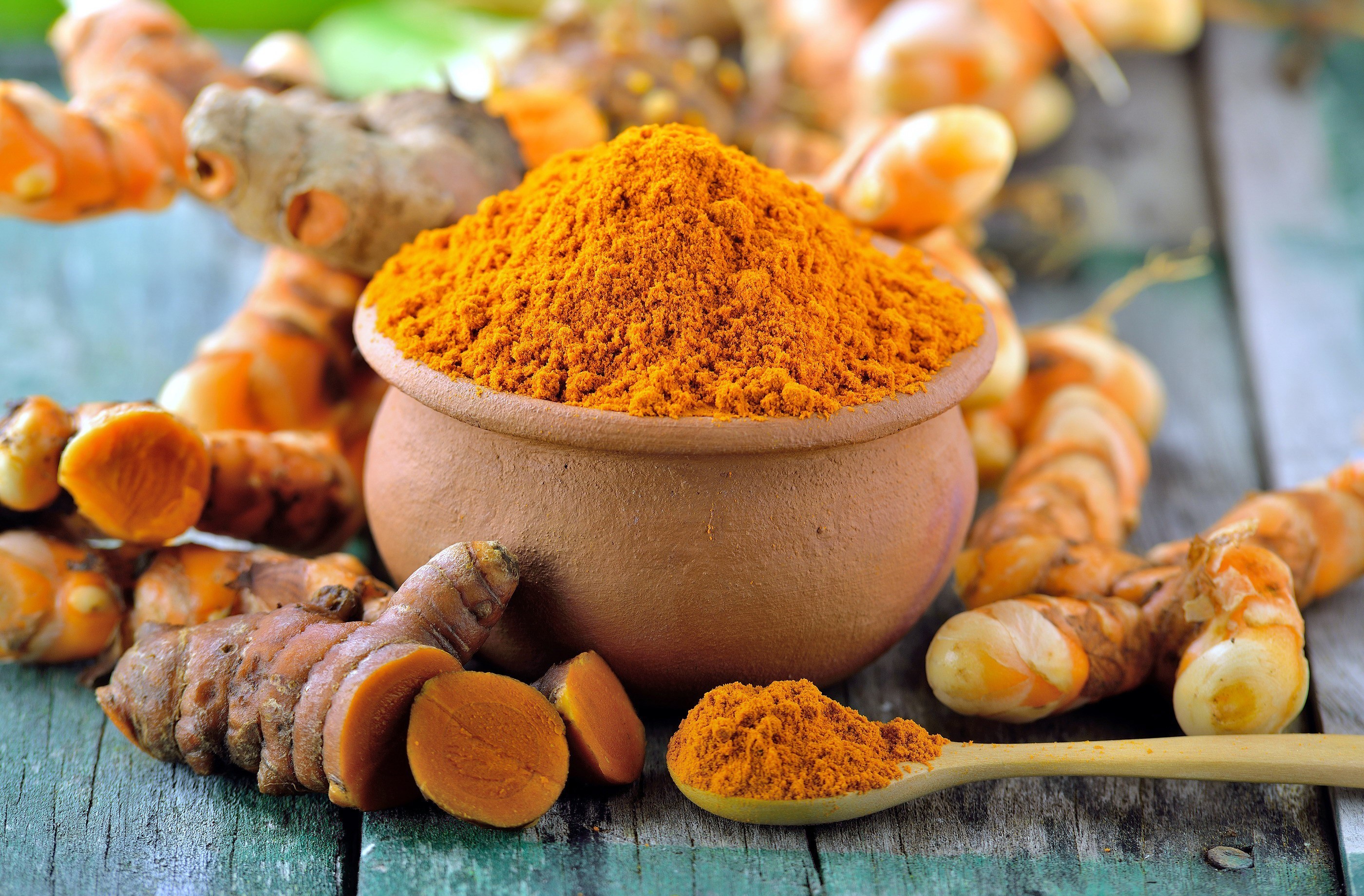 Turmeric powder and roots in a clay pot and spoon HD Wallpaper