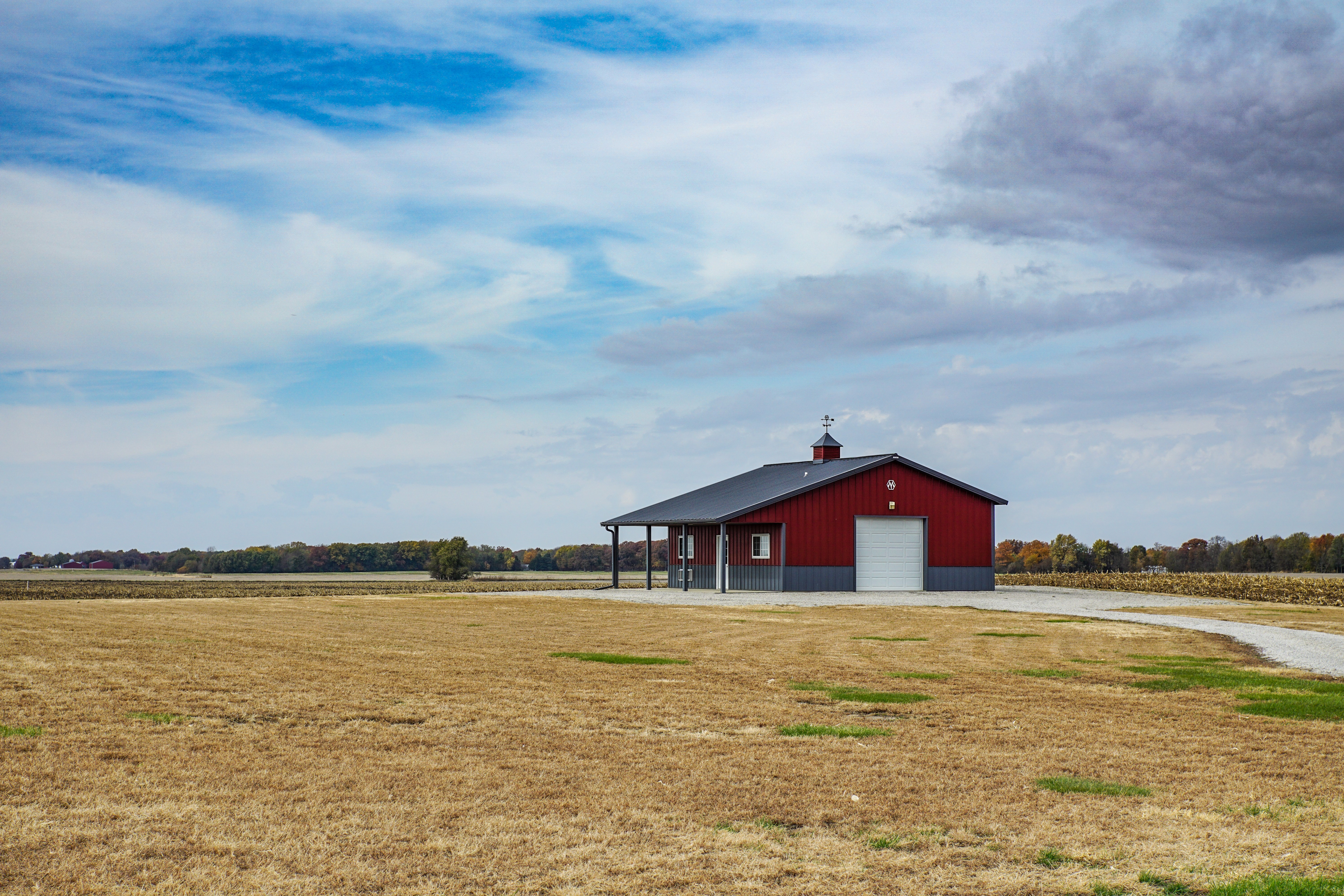Red barn in a dry field under a cloudy sky HD Wallpaper